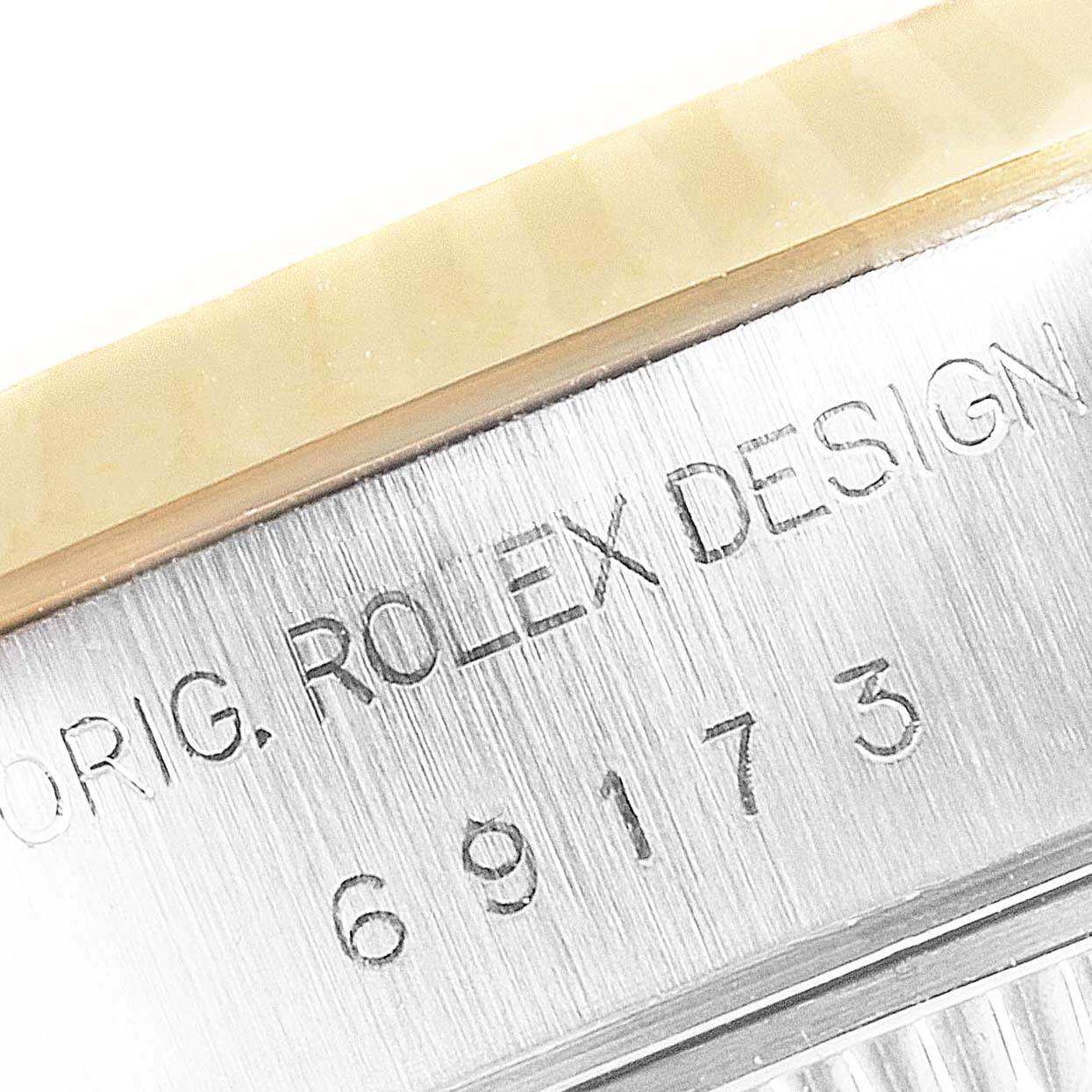 The image shows a close-up of the engraved serial number and part of the bezel on a Rolex Datejust 69173 Women's Steel and Gold (two tone) White Dial 69173 Women's Steel and Gold (two tone) White Dial watch.