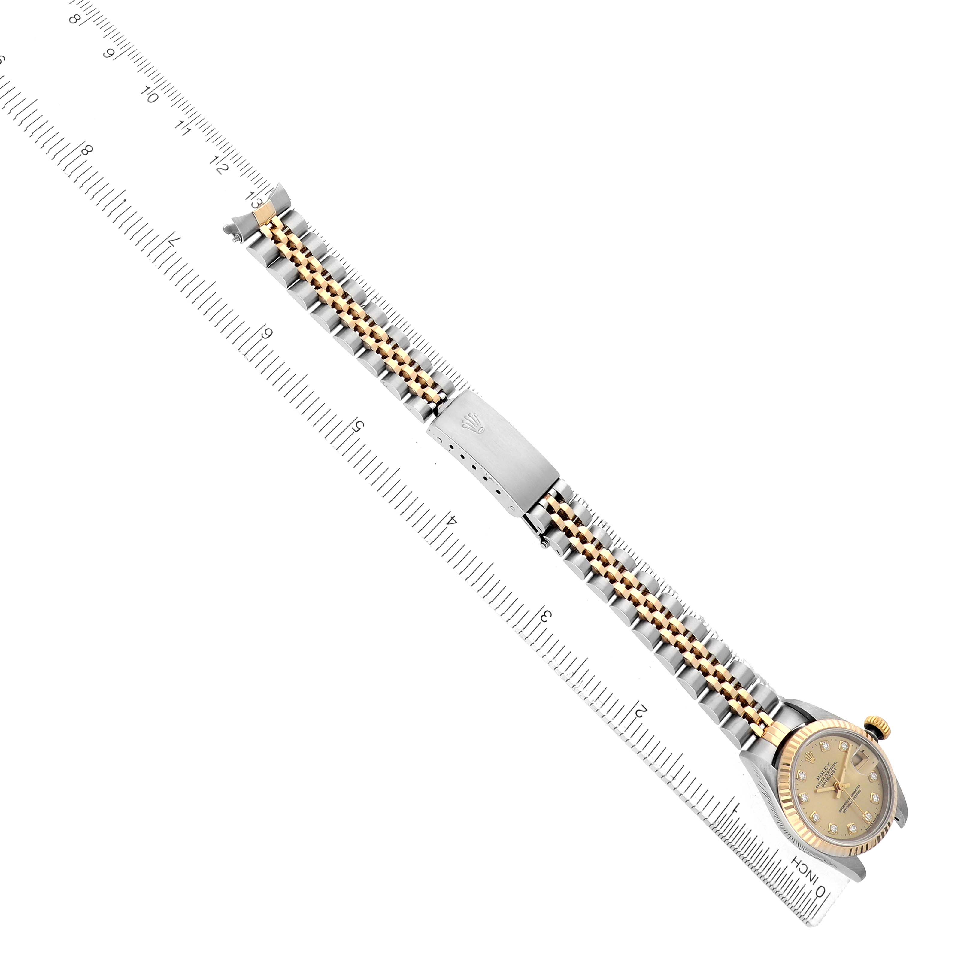 The Rolex Datejust 69173 Women
s Steel and Gold (two tone) Champagne Dial watch is shown from a top-down angle, displaying its bracelet, clasp, and face alongside a ruler for scale.