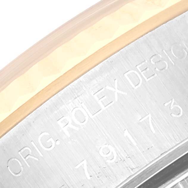 The image shows a close-up angle of the outer casing, highlighting part of the serial number and "ORIG. ROLEX DESIGN" engraving on a Rolex Datejust 79173 Women's Steel and Gold (two tone) White Dial 79173 Women's Steel and Gold (two tone) White Dial.