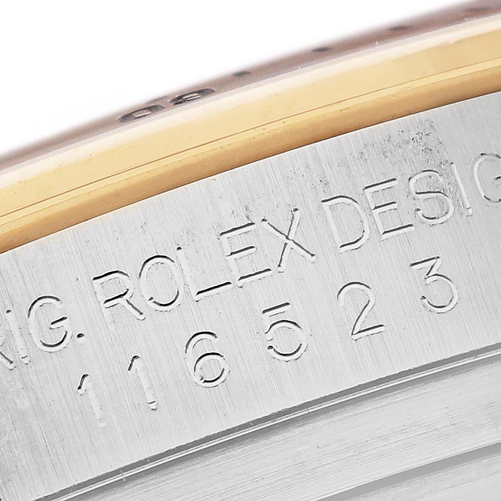 The image shows a close-up of the engraved serial number and "Rolex Design" text on the case side of a Rolex Daytona 116523 Men
s Steel and Gold (two tone) Silver Dial 116523 Men
s Steel and Gold (two tone) Silver Dial watch.