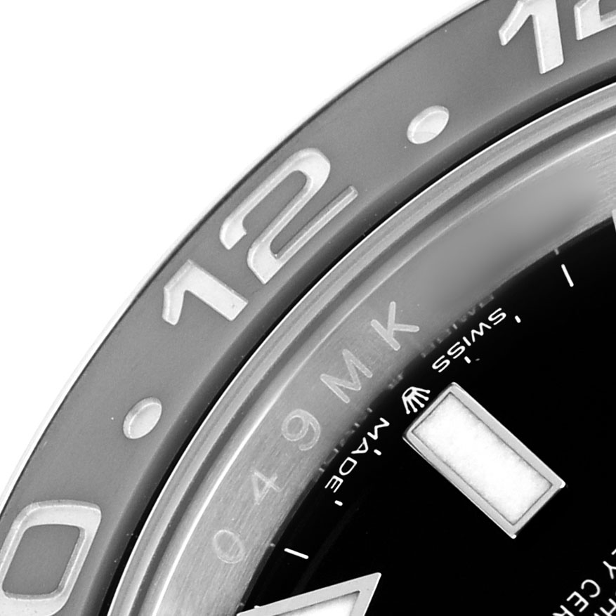The image shows a close-up of the bezel with "12” and dial details of a Rolex GMT-Master 126710GRNR Men's Stainless Steel Black Dial.