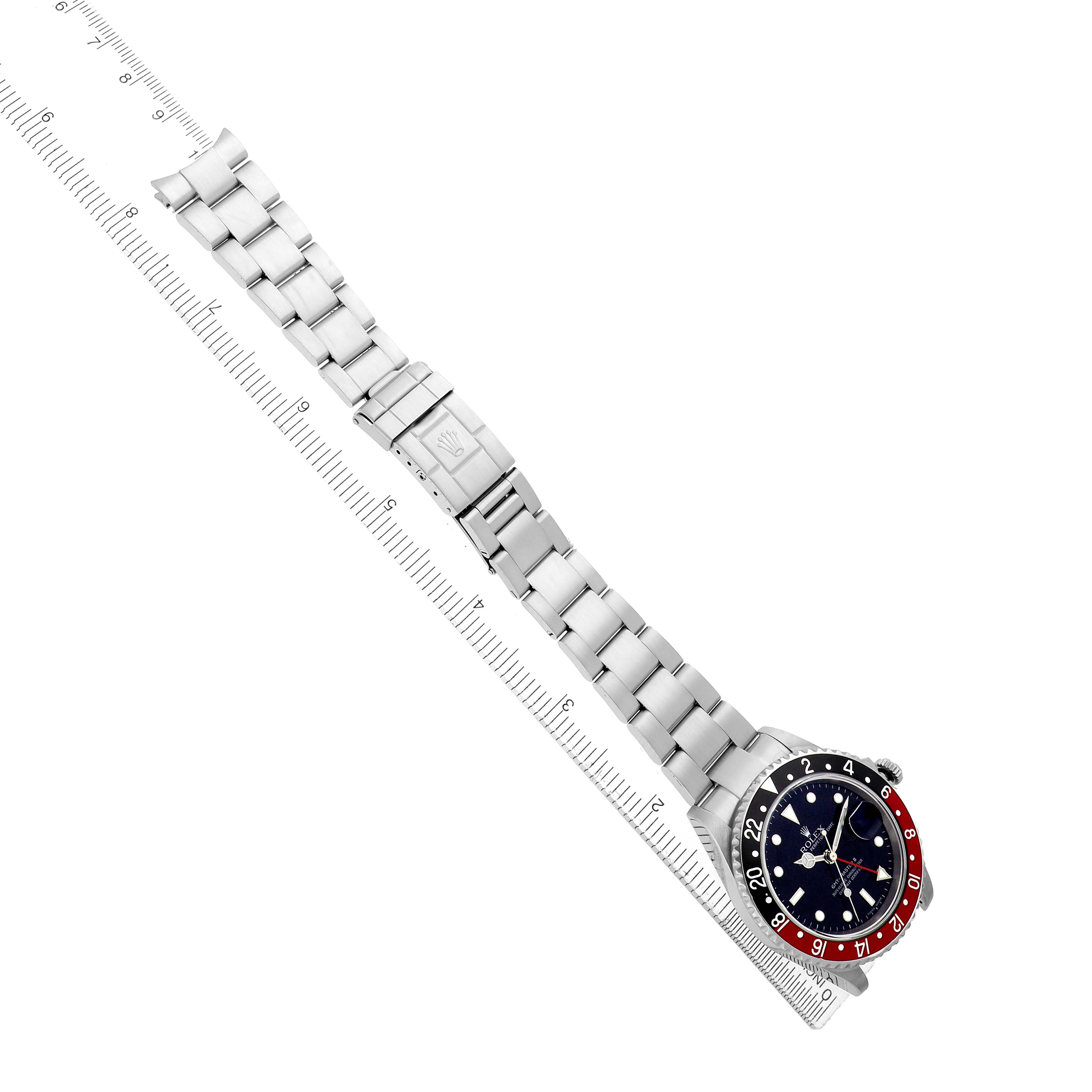 The Rolex GMT-Master 16710 Men
s Stainless Steel Black Dial watch is shown laid flat from an overhead angle, displaying the face and entire metal bracelet alongside a ruler.