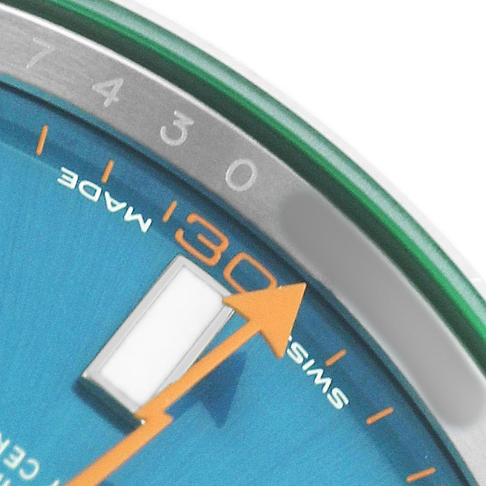 The image shows a close-up of the Rolex Milgauss 116400GV Men's Stainless Steel Blue Dial watch, focusing on the dial's edge, minute markers, and part of the orange second hand.