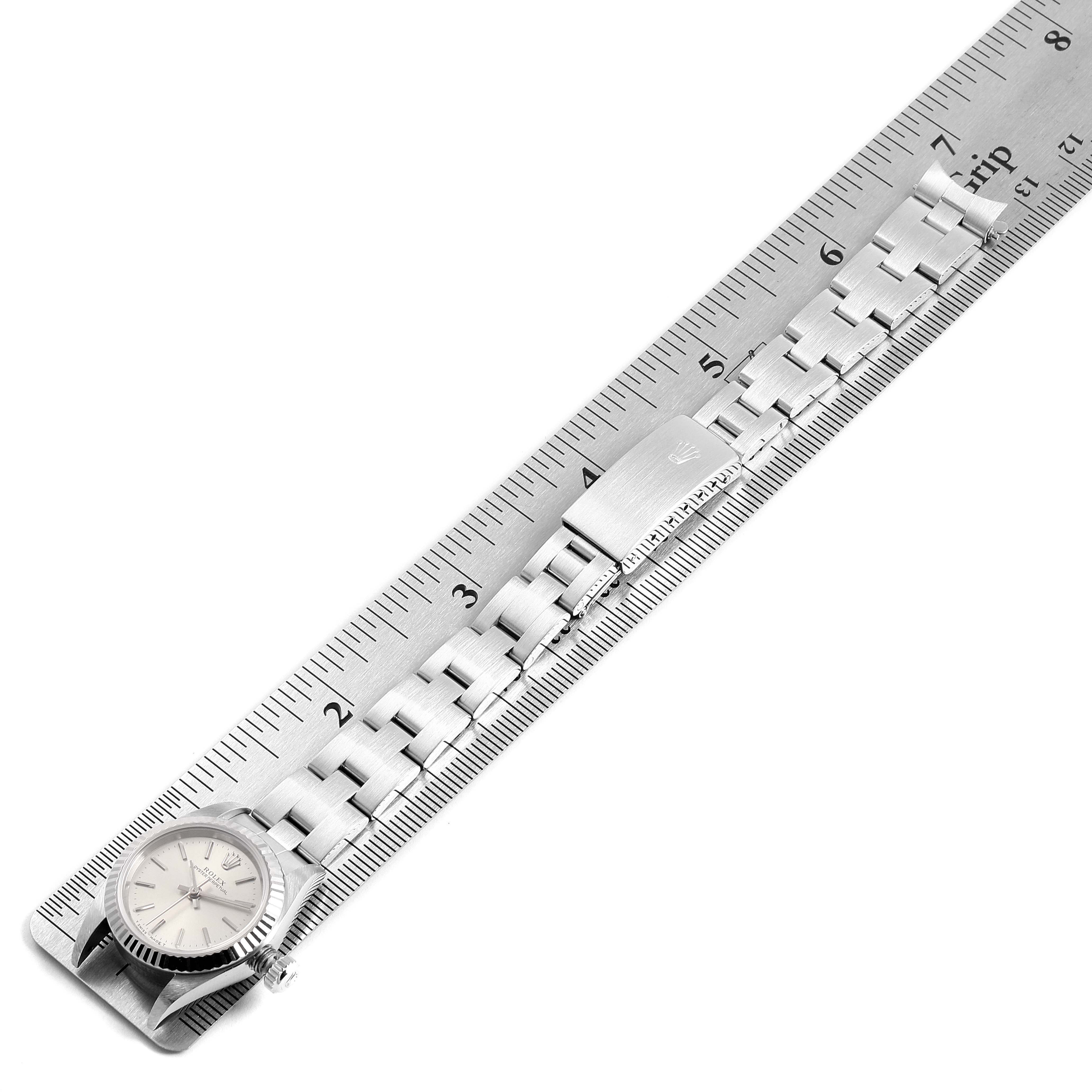 The image shows a Rolex Oyster Perpetual 67194 Women's Stainless Steel Silver Dial 67194 Women's Stainless Steel Silver Dial watch with its stainless steel bracelet laid along a ruler.