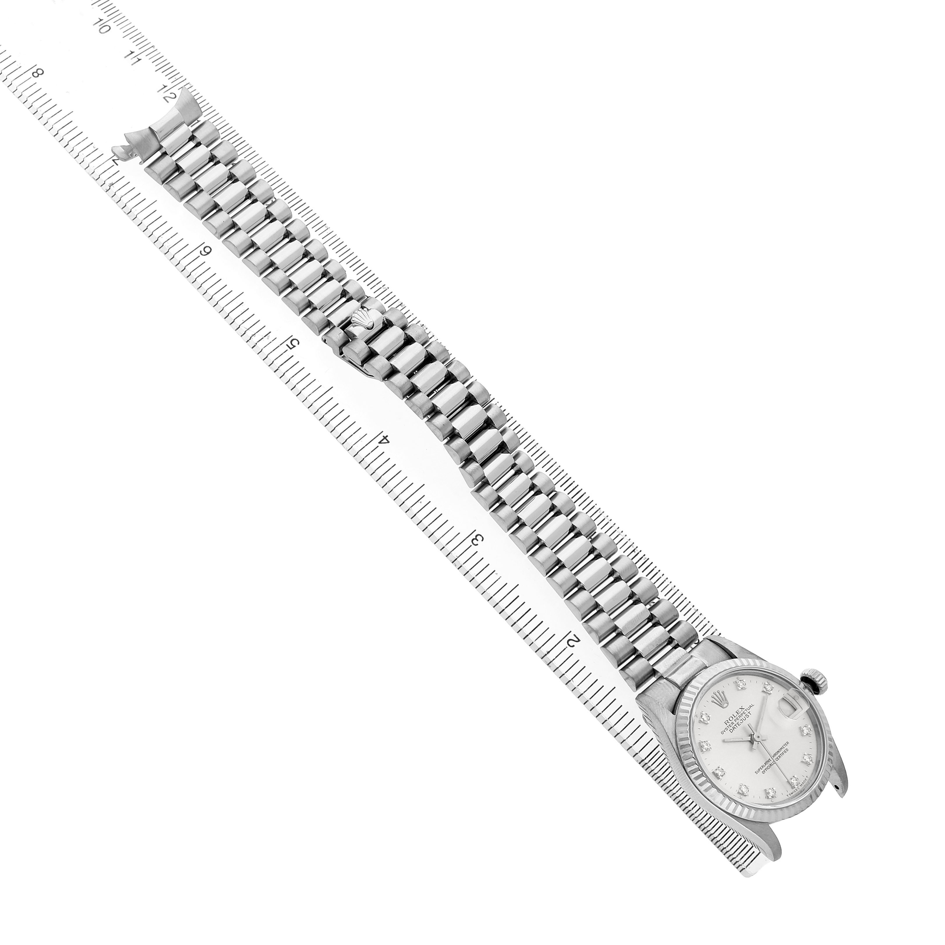 The Rolex President 68279 Women's White Gold Silver Dial watch is shown from an angled top-down view, displaying the dial and full bracelet alongside a ruler.