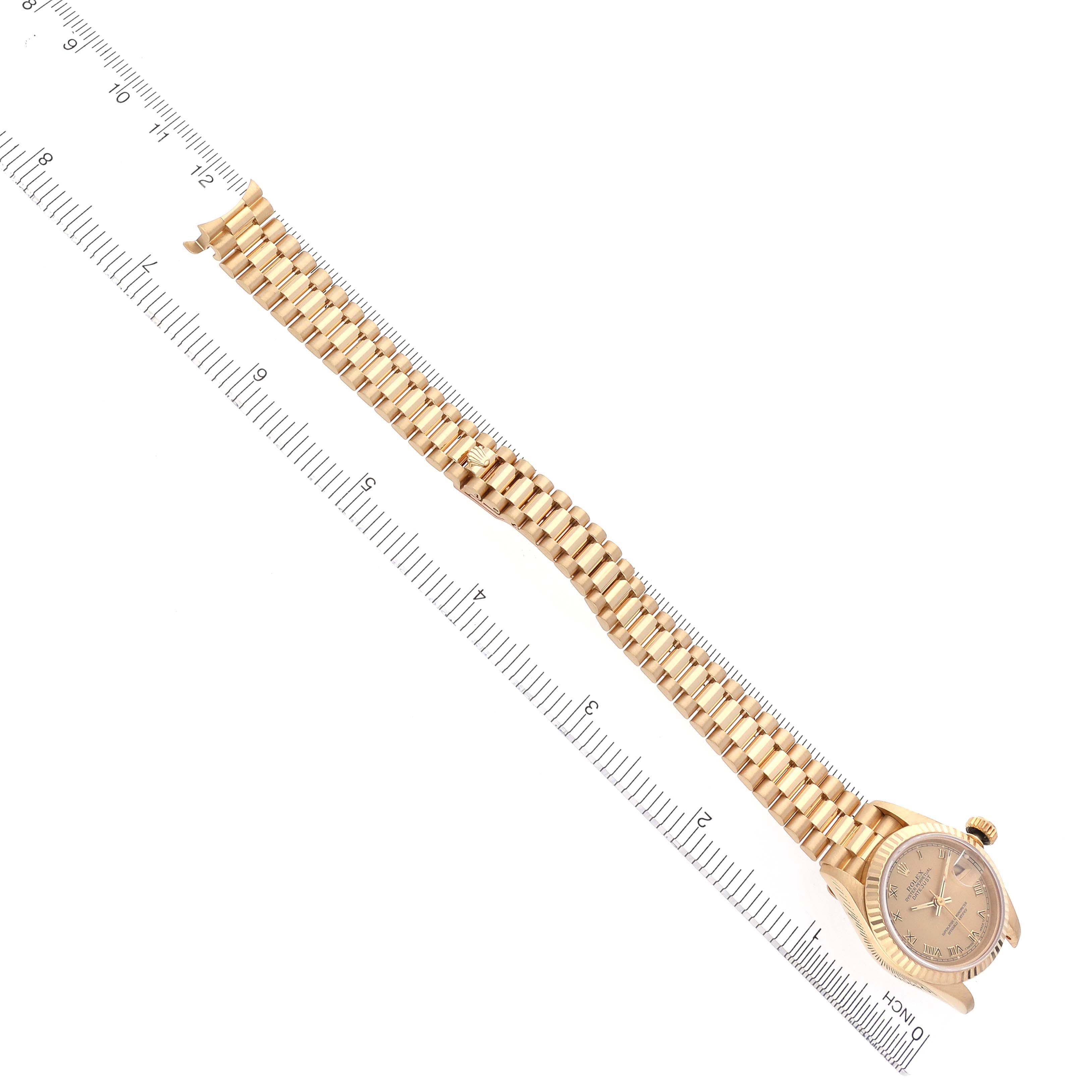 The Rolex President 69178 Women's Yellow Gold Champagne Dial 69178 Women's Yellow Gold Champagne Dial watch is shown at a slight diagonal, displaying its band and face alongside a measuring scale.