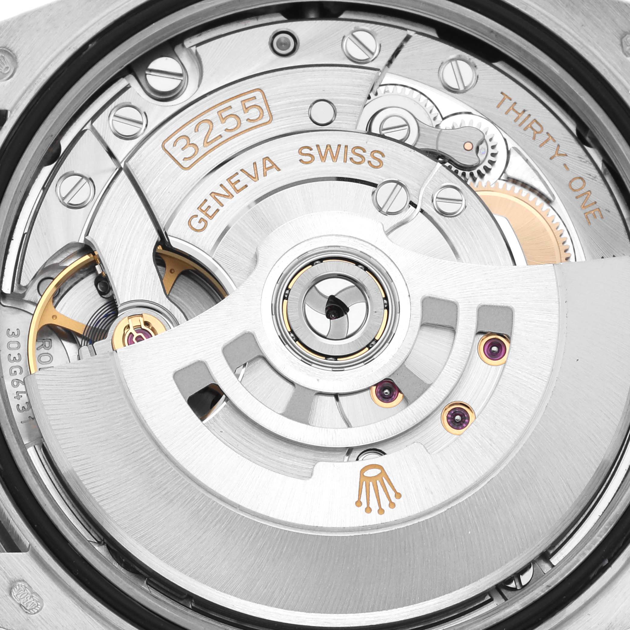 The image shows a close-up of the movement mechanism of a Rolex President 128349 Men
s White Gold Blue Dial 128349 Men
s White Gold Blue Dial model watch, highlighting gears and engravings.