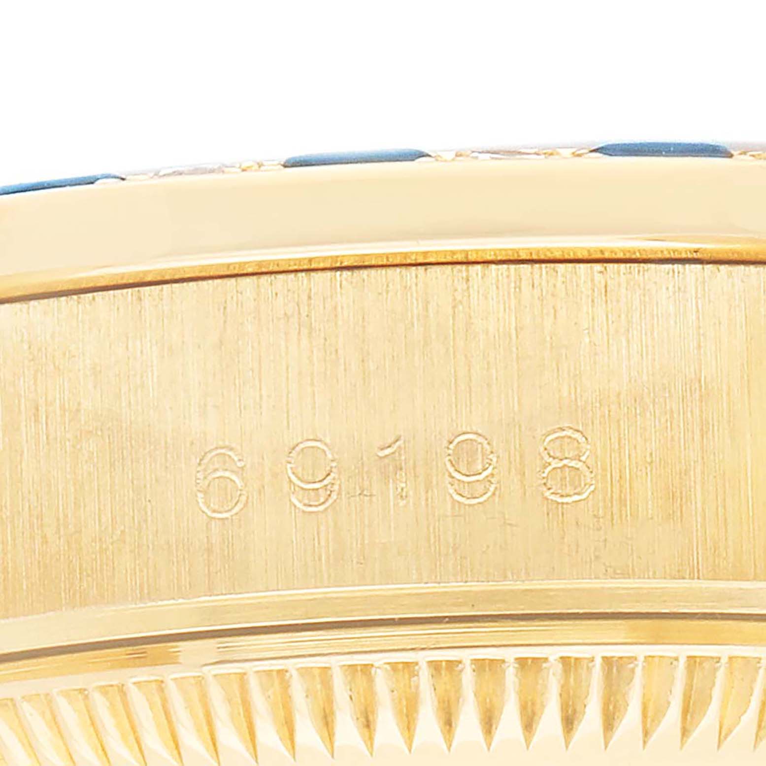 The image shows the side of a Rolex President 69198 Women
s Yellow Gold Champagne Dial model watch focusing on the case with engraved numbers.