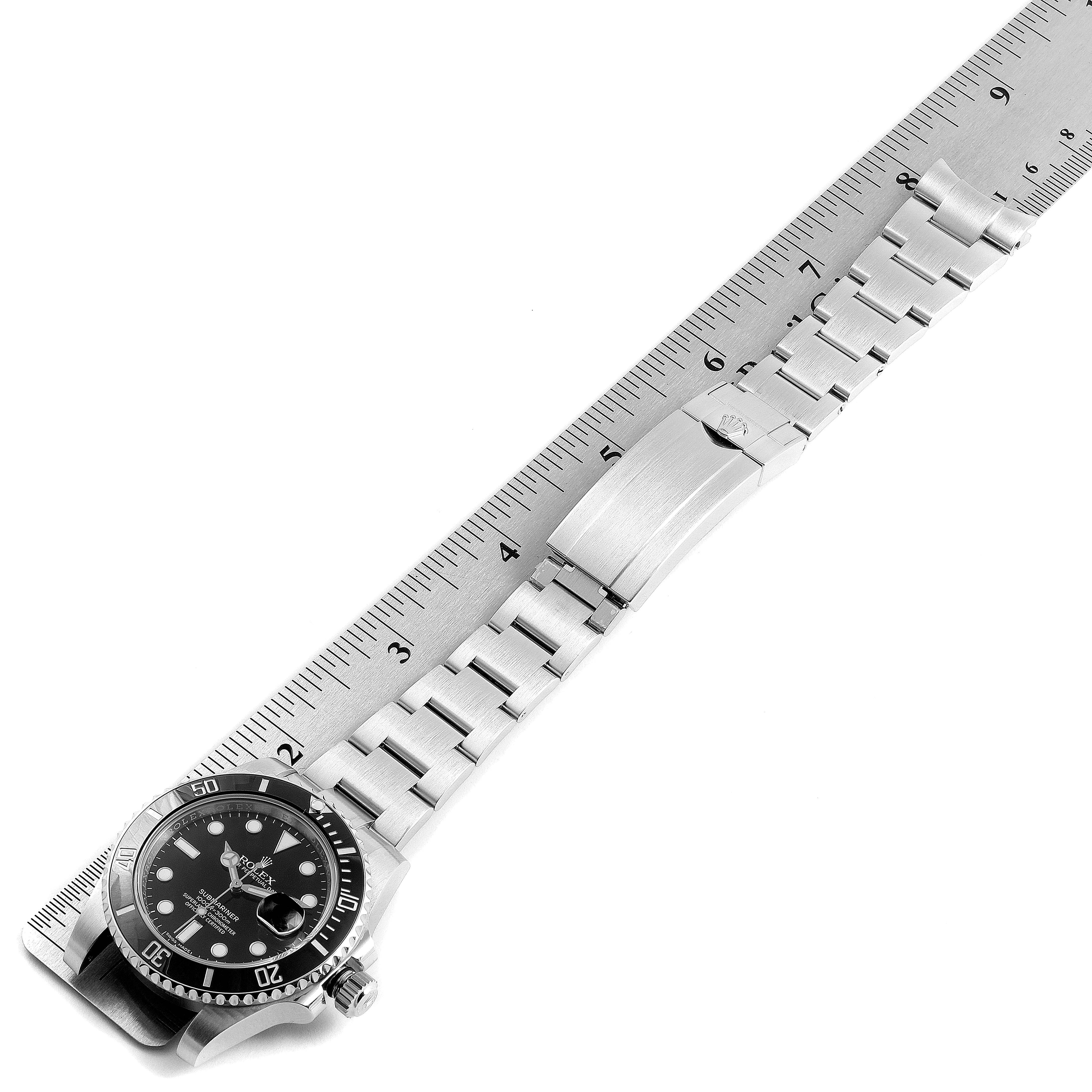 This image shows a top-down view of a Rolex Submariner 116610 Men's Stainless Steel Black Dial 116610 Men's Stainless Steel Black Dial watch alongside a ruler, highlighting its stainless steel bracelet and clasp.