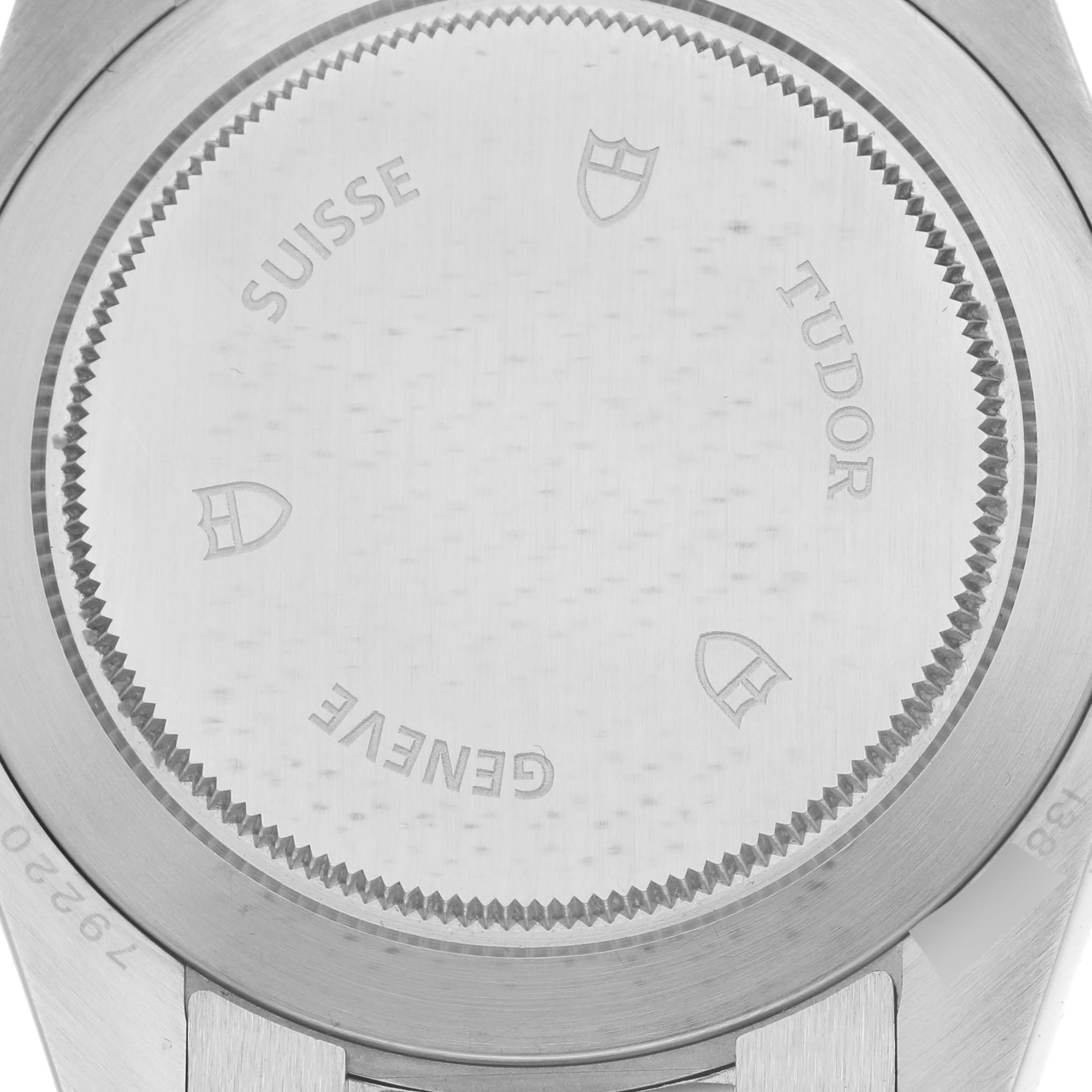 The image shows the case back of the Tudor Heritage Black Bay 79220B Men
s Stainless Steel Black Dial 79220B Men
s Stainless Steel Black Dial watch, featuring etched branding and a ridged edge.