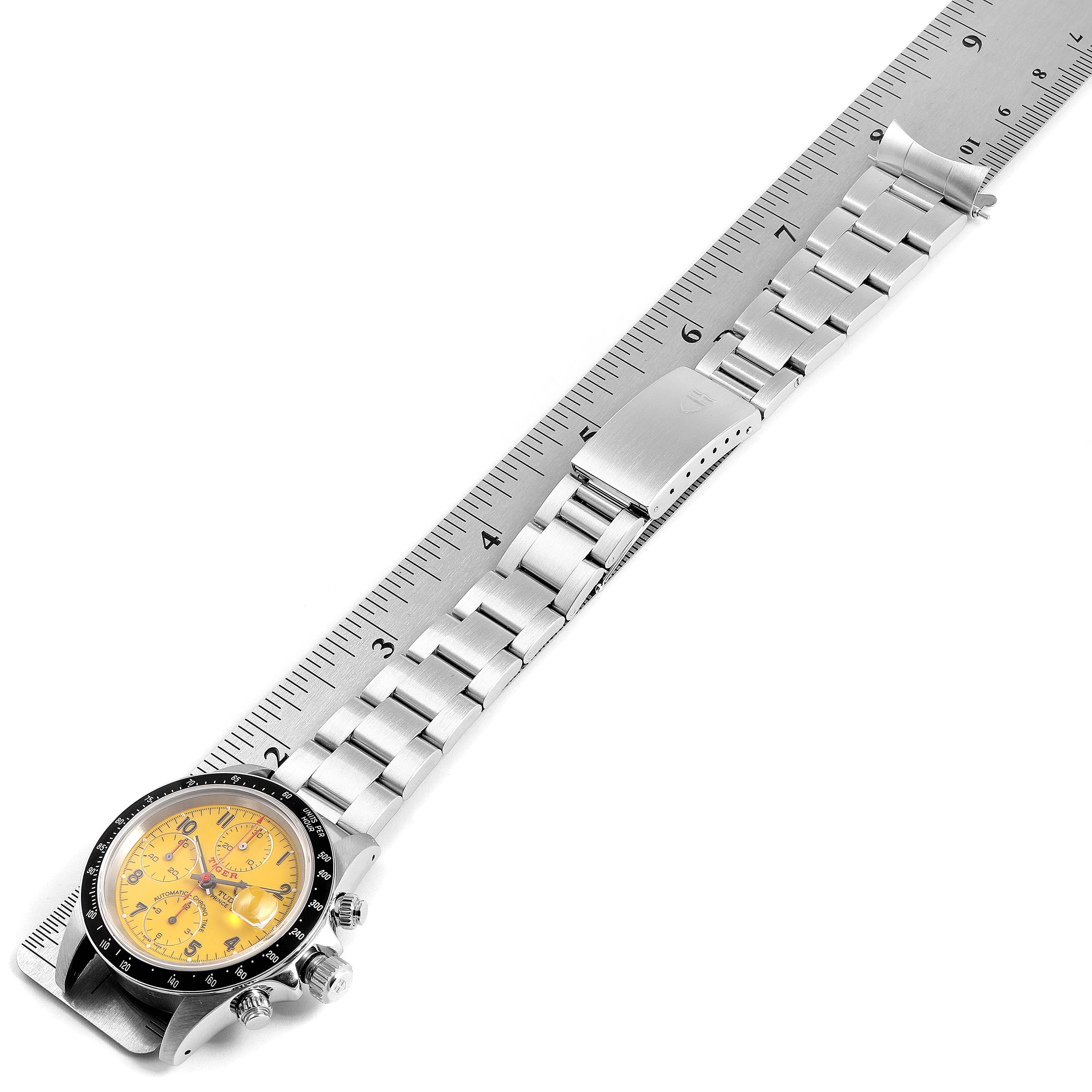The image displays a Tudor Tiger 79260 Men's Stainless Steel Yellow Dial 79260 Men's Stainless Steel Yellow Dial model watch with a yellow dial and a stainless steel bracelet on a ruler, viewed from a top angle.