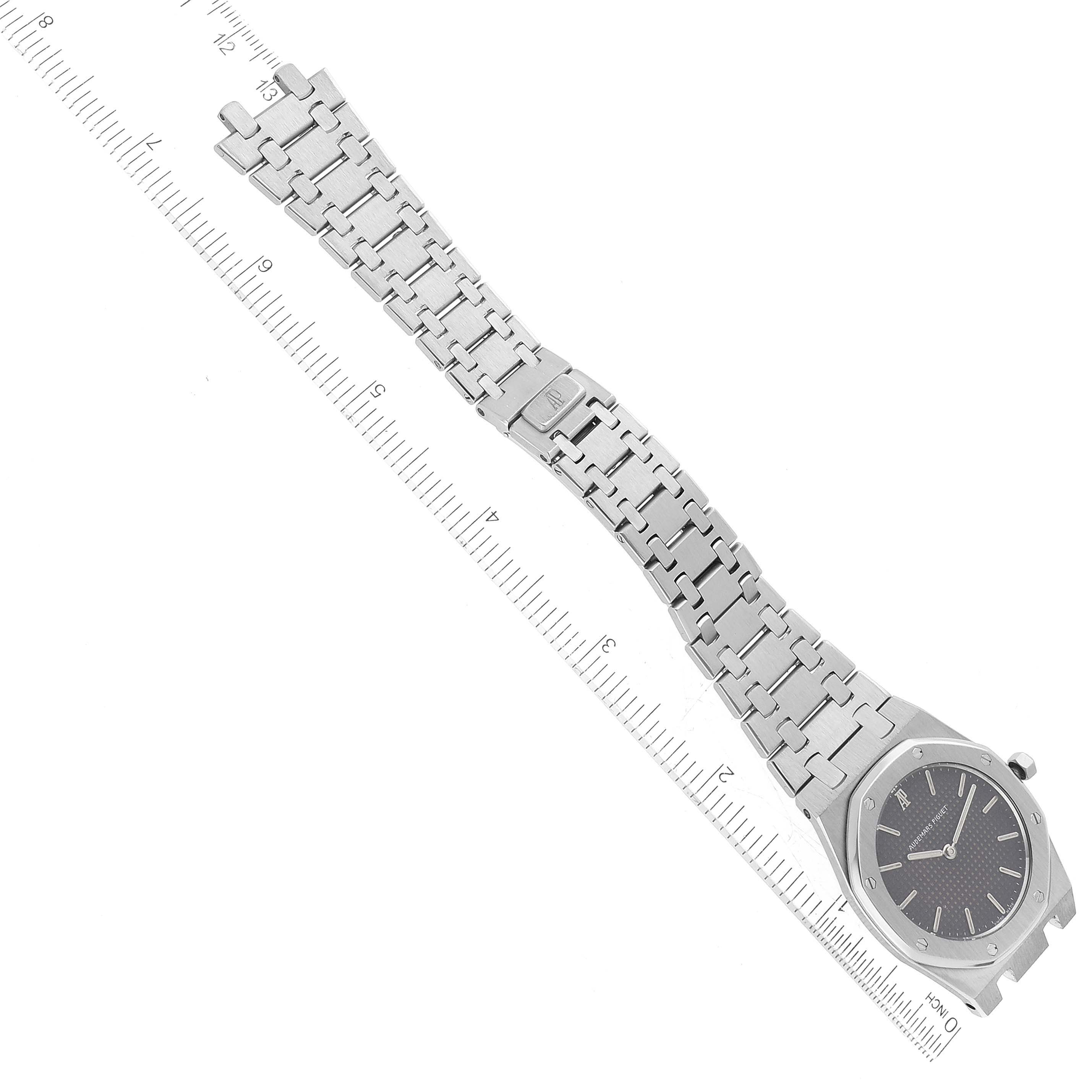 The image shows a top-down view of an Audemars Piguet Royal Oak 56303ST Men's Stainless Steel Black Dial 56303ST Men's Stainless Steel Black Dial watch, including the face, bracelet, and clasp, positioned alongside a ruler.