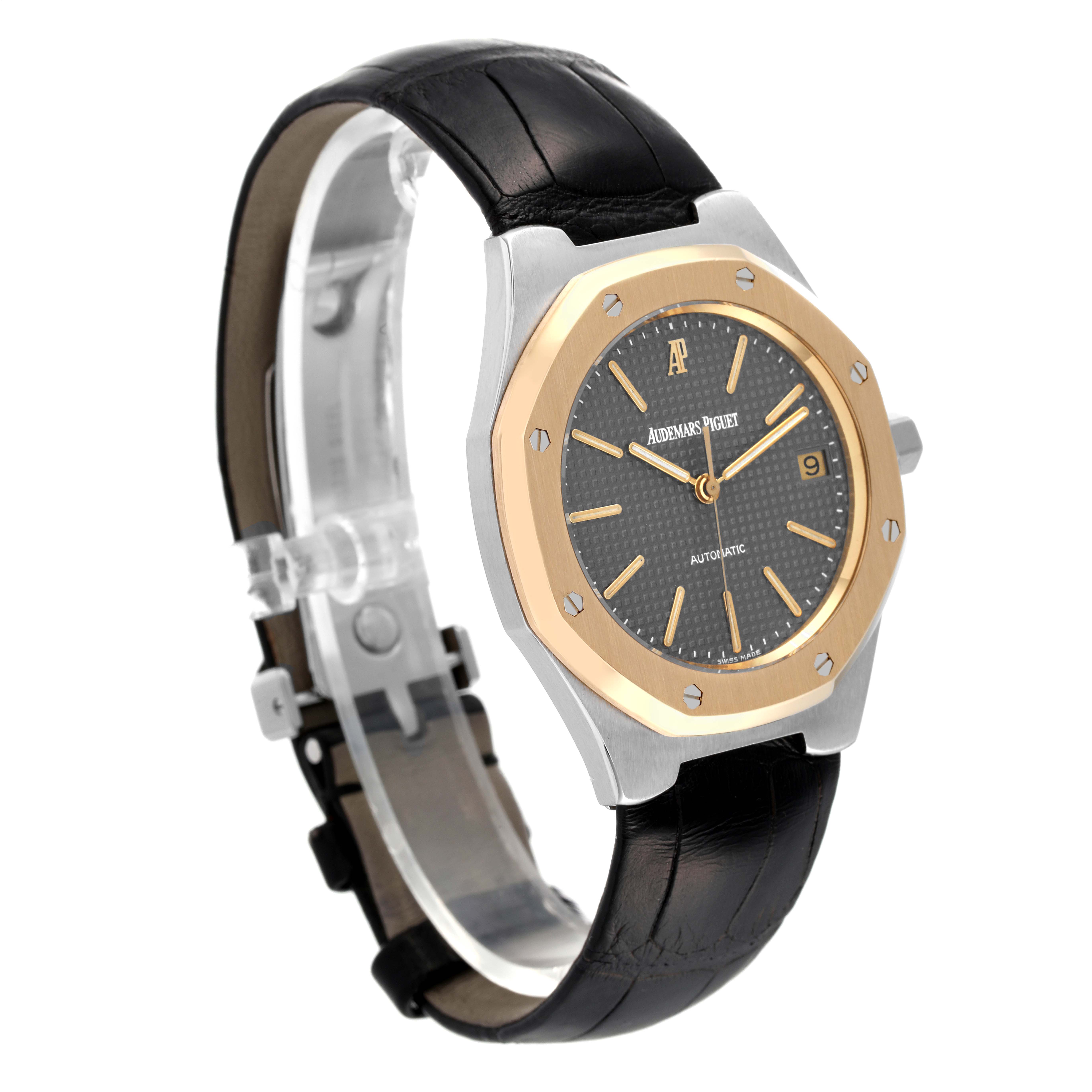 The image shows a side angle of an Audemars Piguet Royal Oak Men
s Steel and Gold (two tone) Grey Dial Men
s Steel and Gold (two tone) Grey Dial watch featuring a black leather strap and a dual-tone case with a gold bezel.