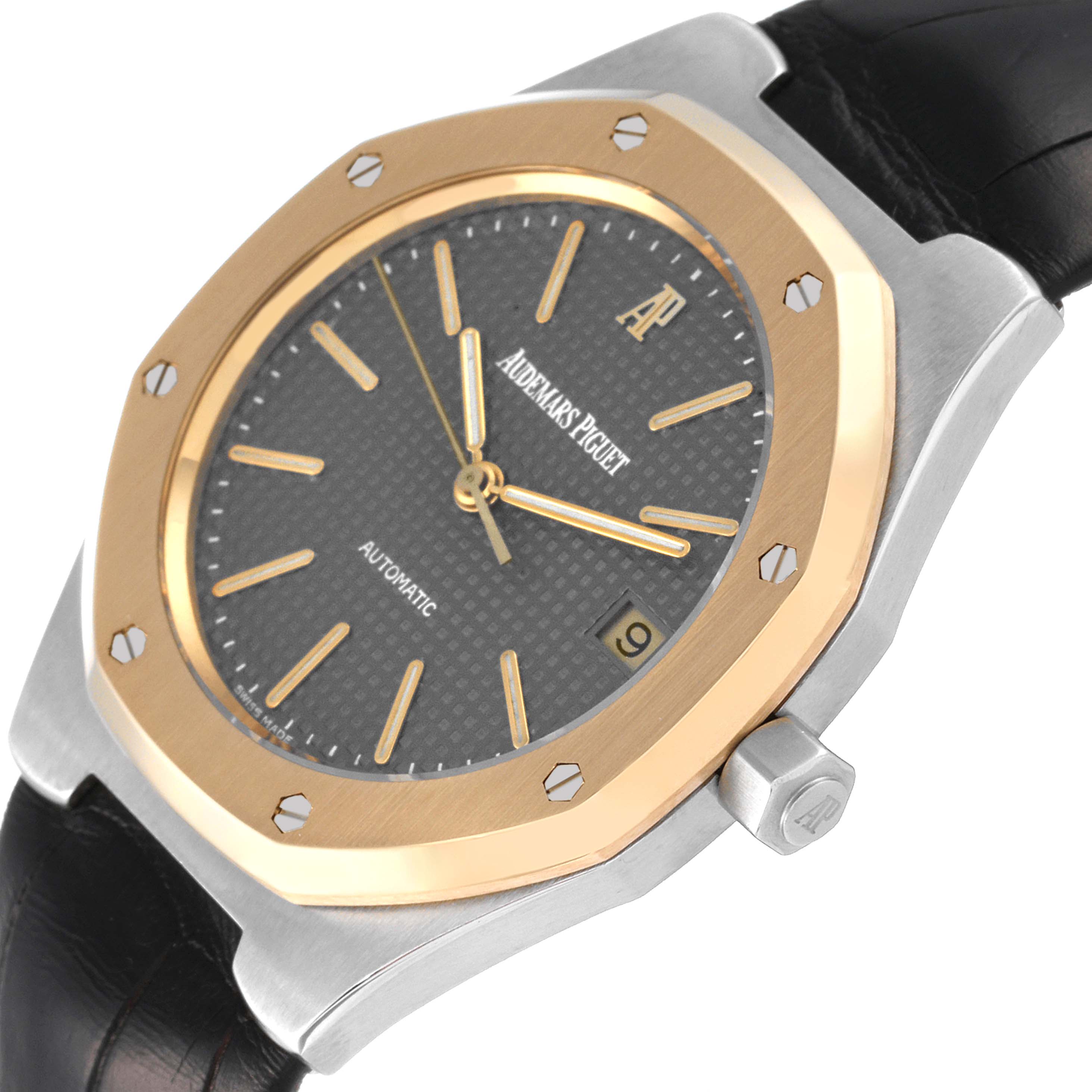 This image shows a close-up of the Audemars Piguet Royal Oak Men
s Steel and Gold (two tone) Grey Dial Men
s Steel and Gold (two tone) Grey Dial
s watch face, bezel, crown, and part of its leather strap from a slight angle.
