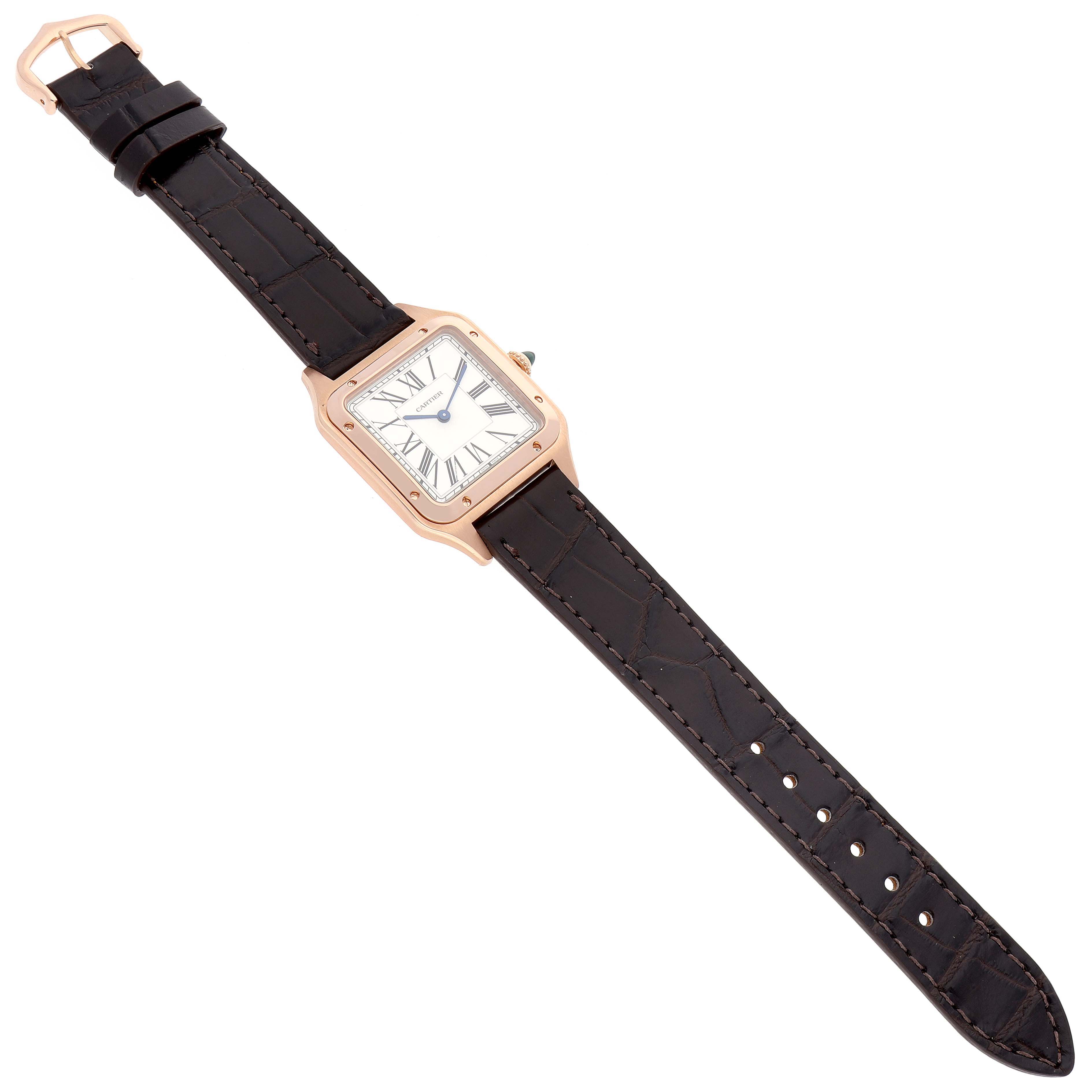 The image shows a top view of a Cartier Santos Dumont WGSA0021 Men's Rose Gold Silver Dial WGSA0021 Men's Rose Gold Silver Dial model watch, featuring a square face and a black leather strap.