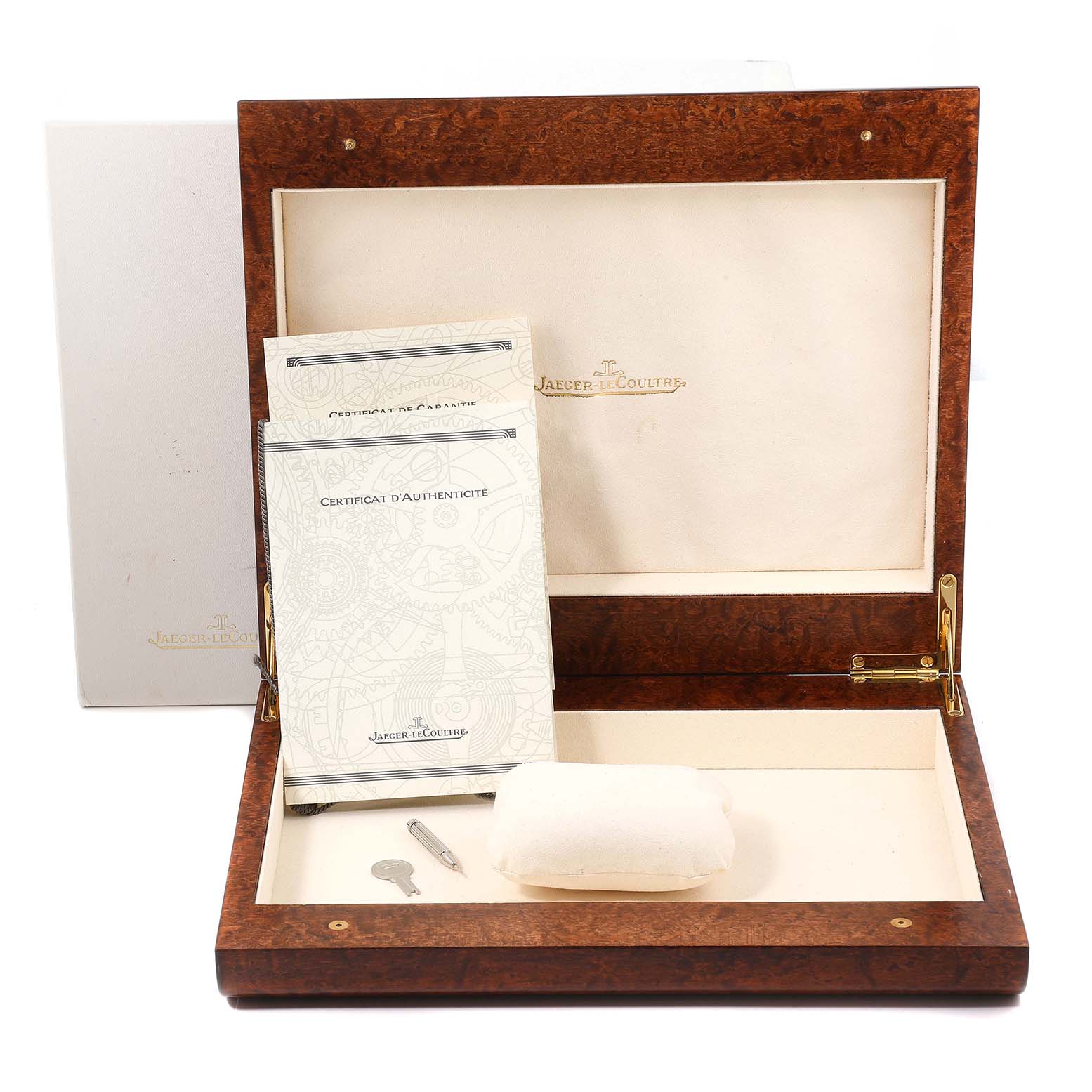 This image shows the open wooden box for a Jaeger LeCoultre Reverso 270.2.582B Men's Rose Gold Silver Dial 270.2.582B Men's Rose Gold Silver Dial watch, including documentation and a small tool inside.