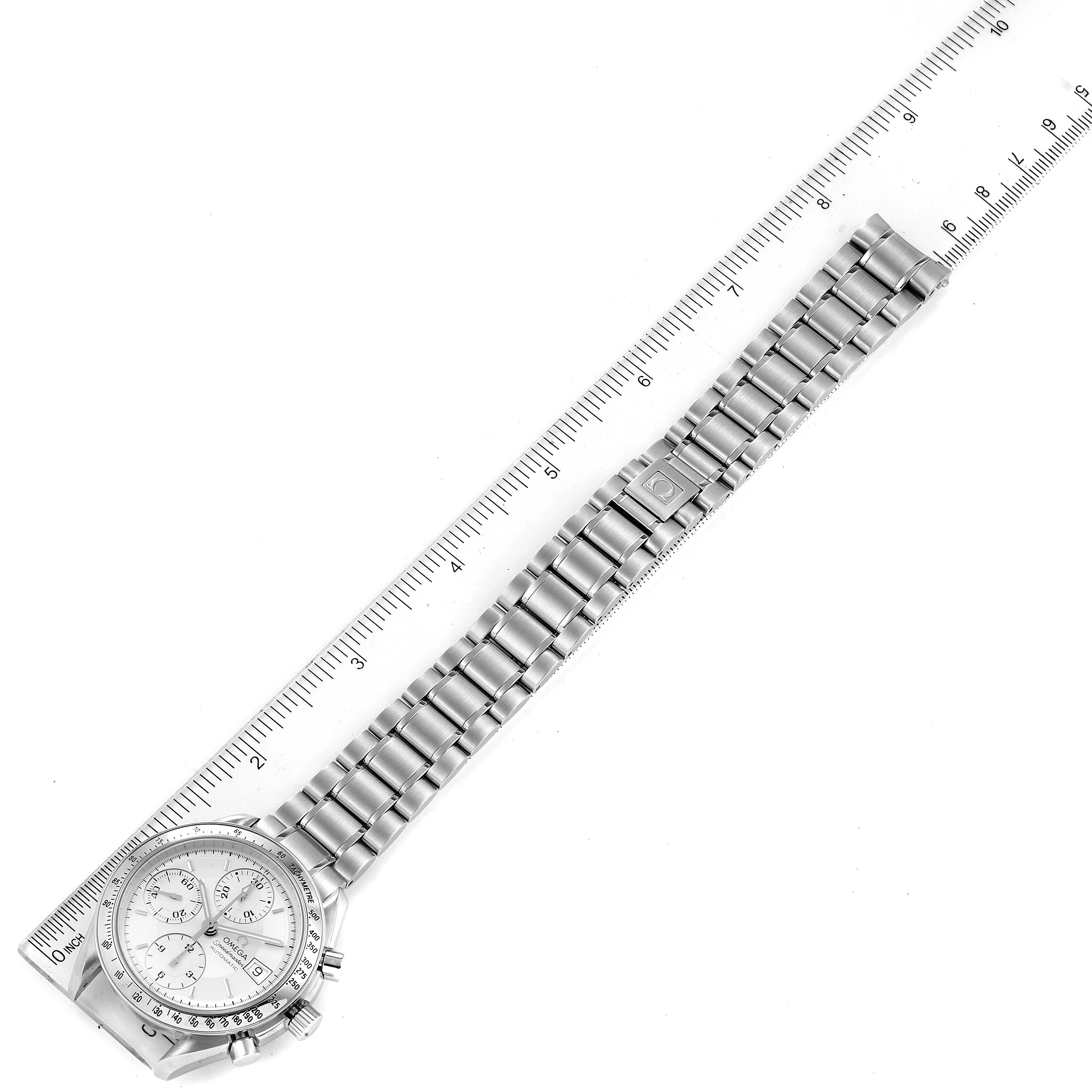 The image shows a top view of an Omega Speedmaster 3513.30.00 Men
s Stainless Steel Silver Dial 3513.30.00 Men
s Stainless Steel Silver Dial watch with its metal band and a ruler for scale.