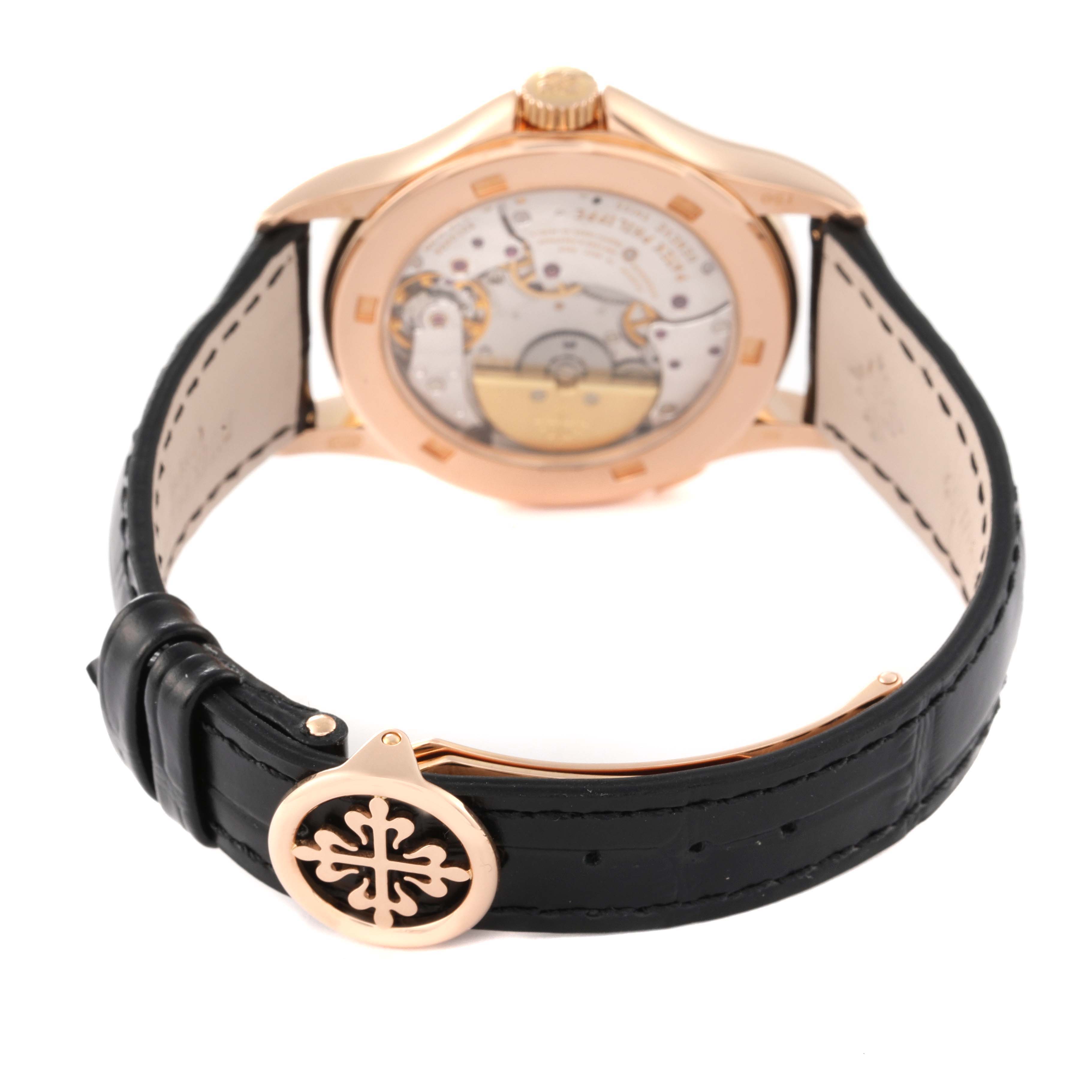 The image shows the back casing and movement of the Patek Philippe Complications 5110R Men's Yellow Gold Silver Dial 5110R Men's Yellow Gold Silver Dial model, along with its black leather strap and clasp.