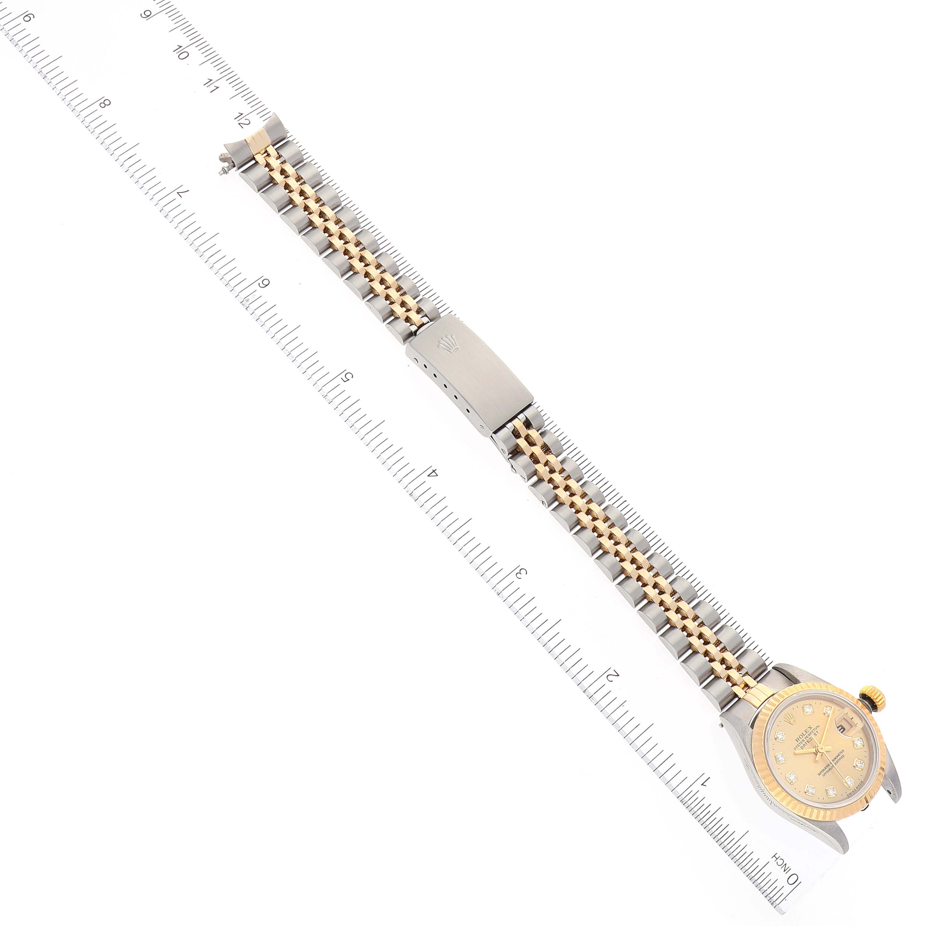 The image shows a Rolex Datejust 69173 Women's Steel and Gold (two tone) Champagne Dial 69173 Women's Steel and Gold (two tone) Champagne Dial watch from a top-down angle, highlighting the face, bezel, and full bracelet along with a ruler for scale.
