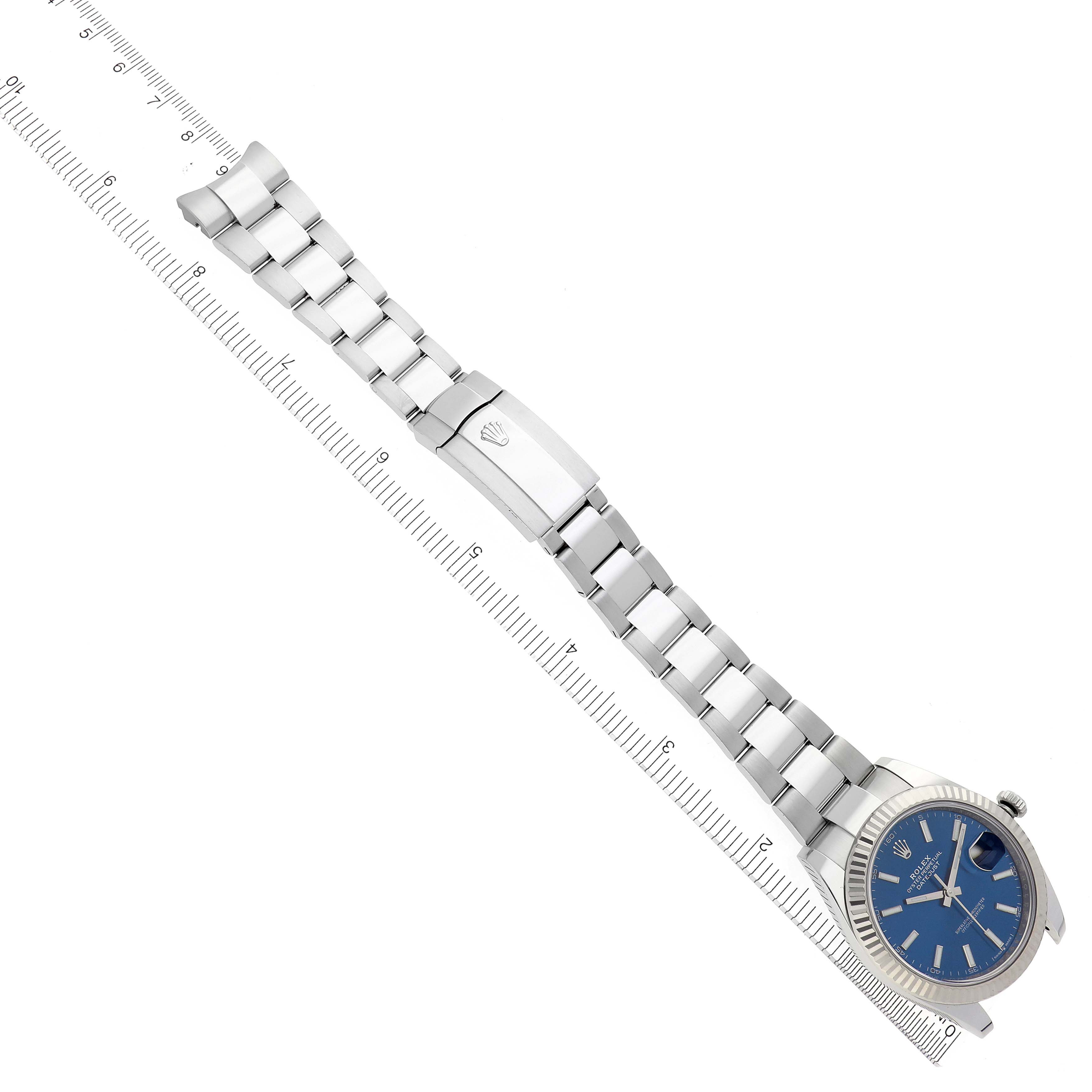 The Rolex Datejust 41 126334 Men
s Stainless Steel Blue Dial 126334 Men
s Stainless Steel Blue Dial is shown from an aerial view, displaying the bracelet, clasp, and face against a ruler.