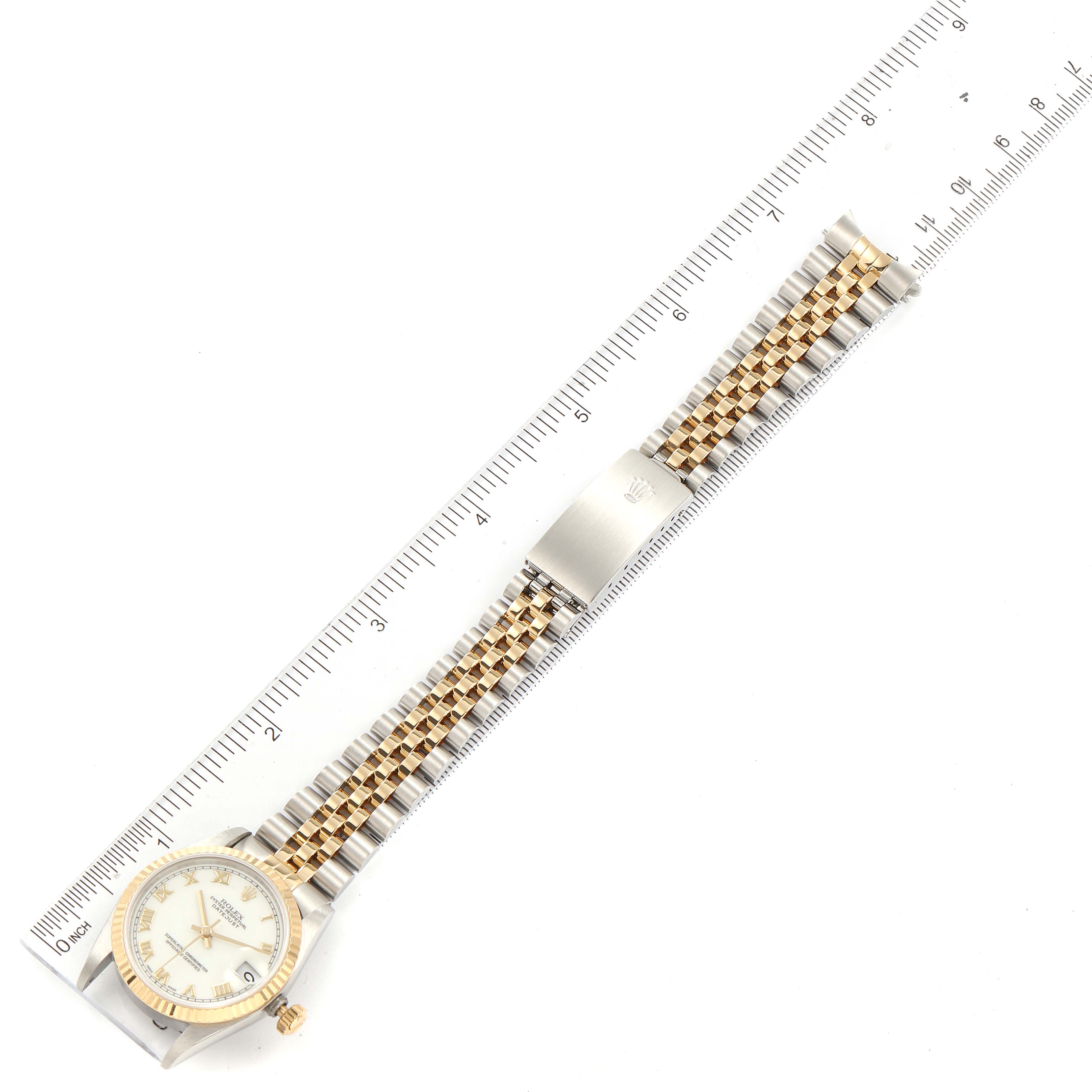The Rolex Mid-Size 68273 Women
s Steel and Gold (two tone) White Dial 68273 Women
s Steel and Gold (two tone) White Dial watch is shown in a flat lay angle with its full strap and face visible, placed on a ruler for scale.