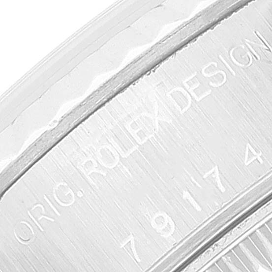 This close-up image shows the engraved edge of the Rolex Datejust 79174 Women's Stainless Steel White Dial 79174 Women's Stainless Steel White Dial watch case, displaying "ORIG. ROLEX DESIGN" and a serial number.