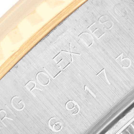 The image shows the side view of a Rolex Datejust 69173G Women's Steel and Gold (two tone) Champagne Dial 69173G Women's Steel and Gold (two tone) Champagne Dial case with engraved text on the metal surface.