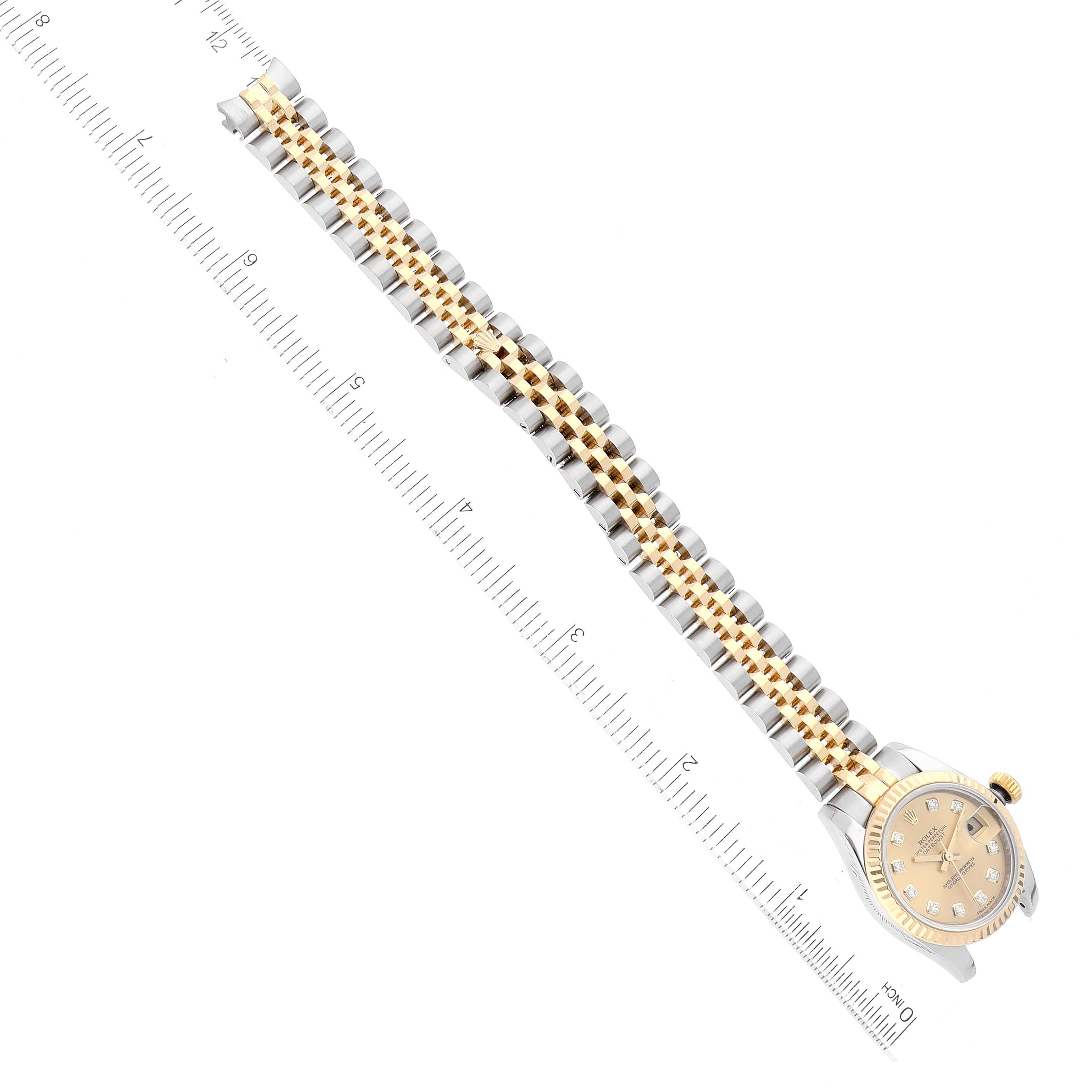 The image shows a Rolex Datejust 179173 Women's Steel and Gold (two tone) Champagne Dial 179173 Women's Steel and Gold (two tone) Champagne Dial watch at a top-down angle, highlighting the face, bracelet, and part of the clasp, with a ruler for scale.