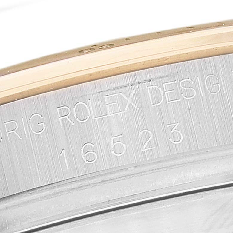 This image shows a close-up of the side bezel and engraved serial number of a Rolex Daytona 16523 Men's Steel and Gold (two tone) Black Dial 16523 Men's Steel and Gold (two tone) Black Dial watch.