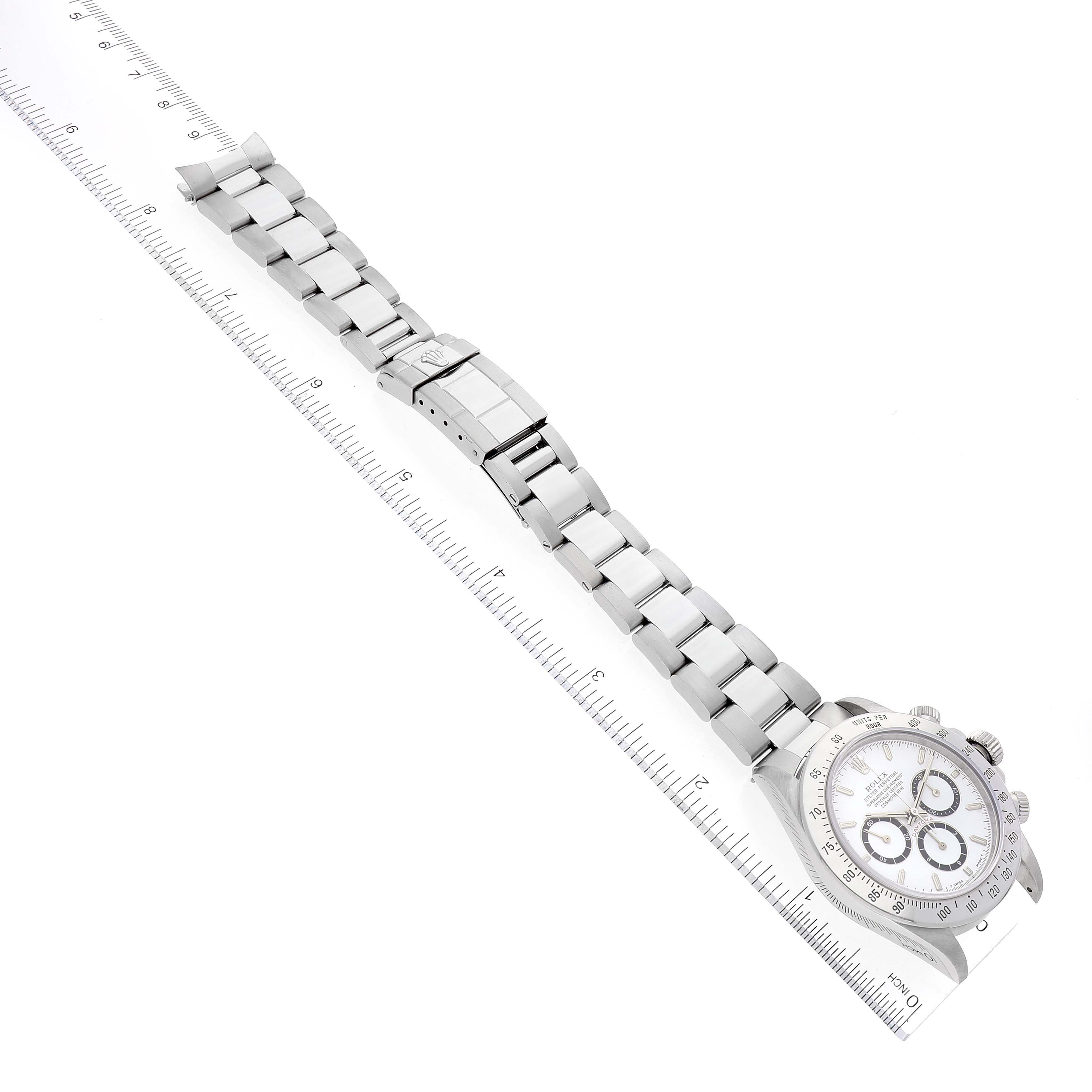 The Rolex Daytona 16520 Men
s Stainless Steel White Dial 16520 Men
s Stainless Steel White Dial watch is shown from an overhead angle, displaying the full bracelet and part of the dial next to a ruler.