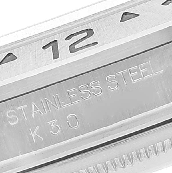 The image shows a close-up of the bezel and case back of the Rolex Explorer 16570 Men
s Stainless Steel Black Dial 16570 Men
s Stainless Steel Black Dial, highlighting the "12" marker and "STAINLESS STEEL" engraving.