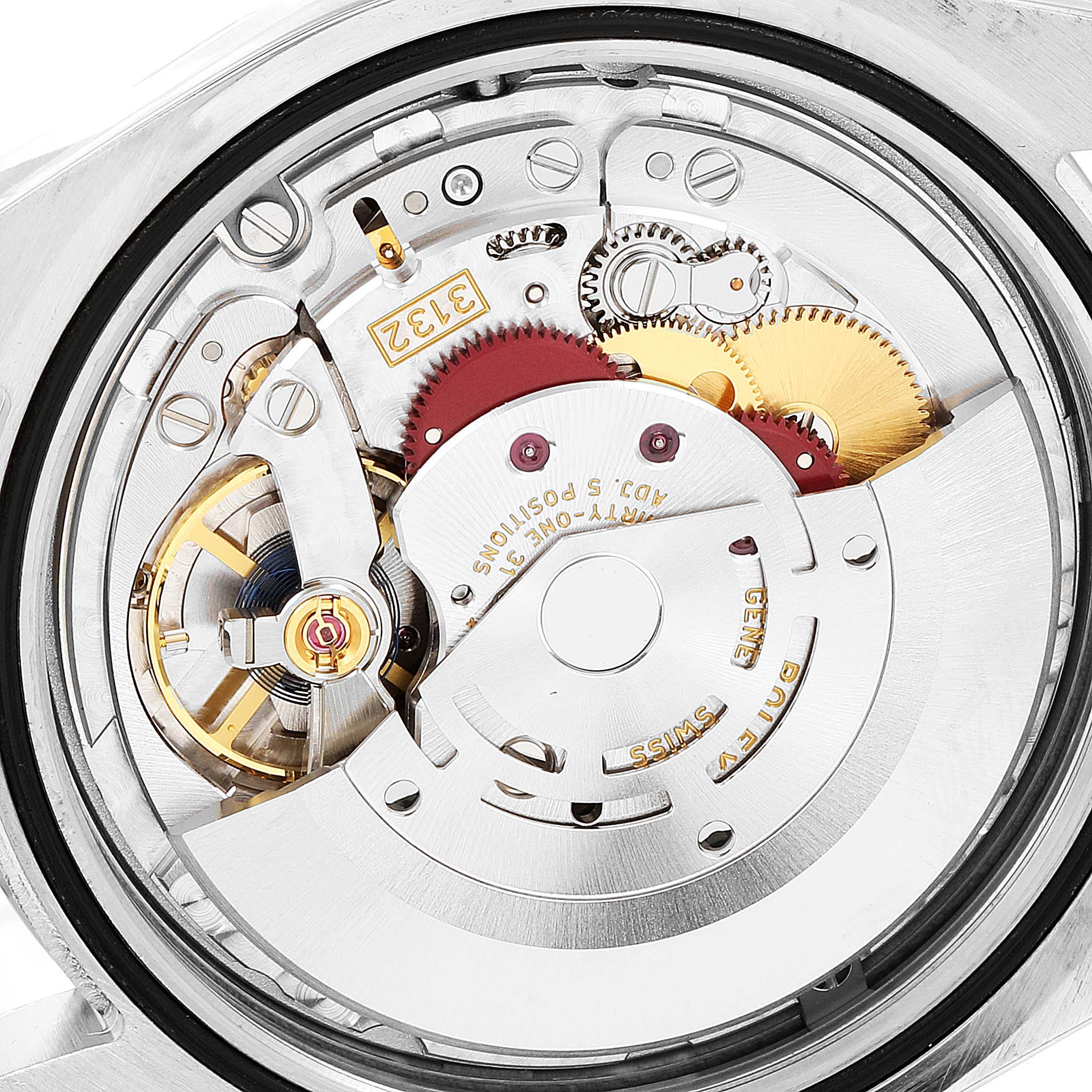 The image shows a close-up of the movement mechanism of a Rolex Oyster Perpetual 114300 Men
s Stainless Steel Blue Dial 114300 Men
s Stainless Steel Blue Dial watch, highlighting its intricate parts and gears.