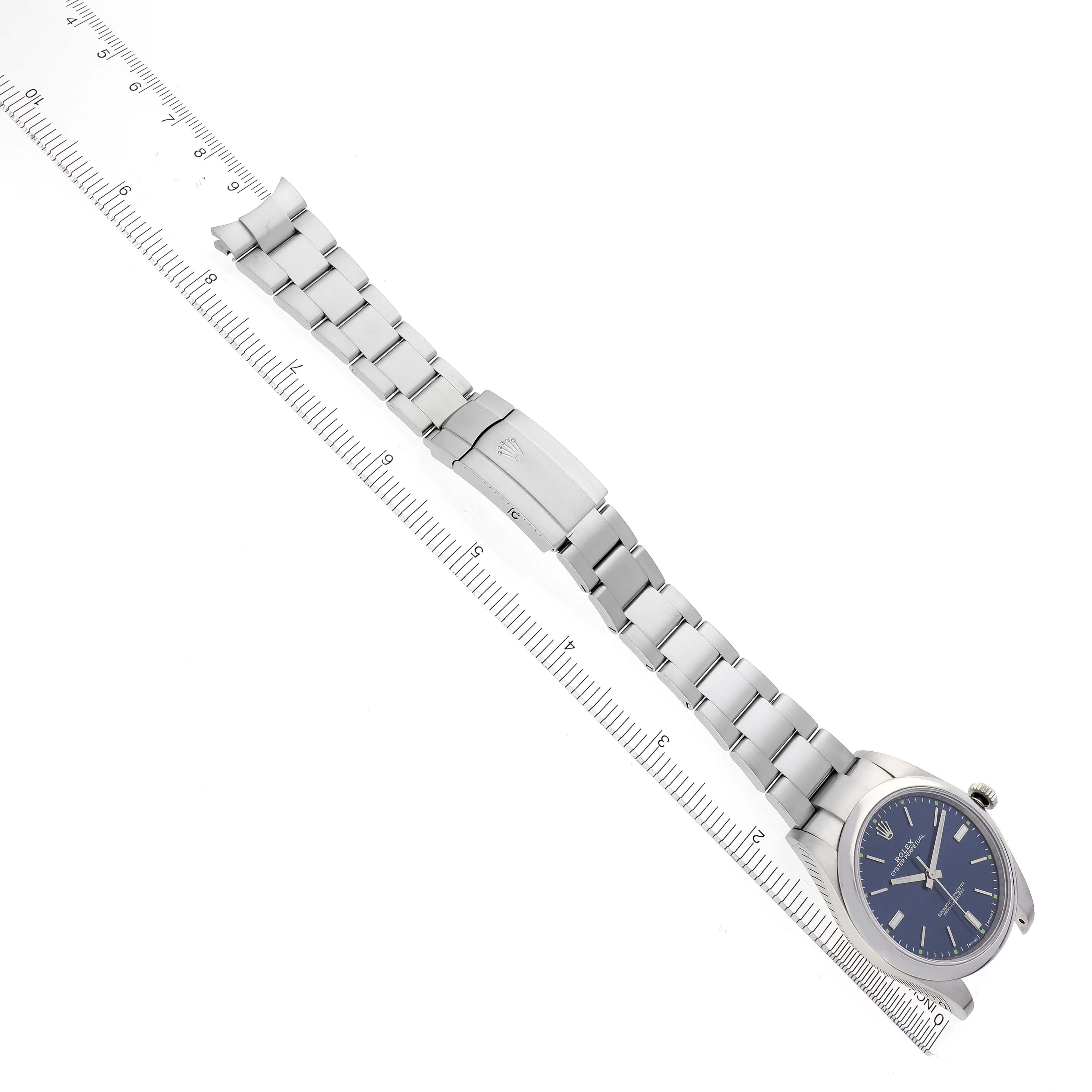 The Rolex Oyster Perpetual 114300 Men's Stainless Steel Blue Dial 114300 Men's Stainless Steel Blue Dial watch is shown in a straight, flat angle displaying the bracelet and clasp alongside a ruler.