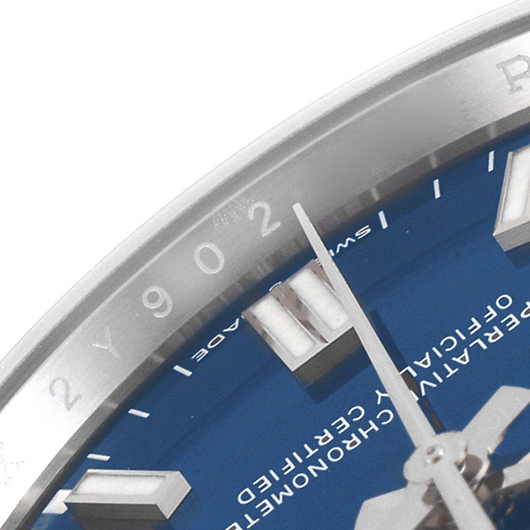 This close-up image of the Rolex Oyster Perpetual 126000 Men
s Stainless Steel Blue Dial 126000 Men
s Stainless Steel Blue Dial model showcases part of the blue dial, hour markers, and bezel.