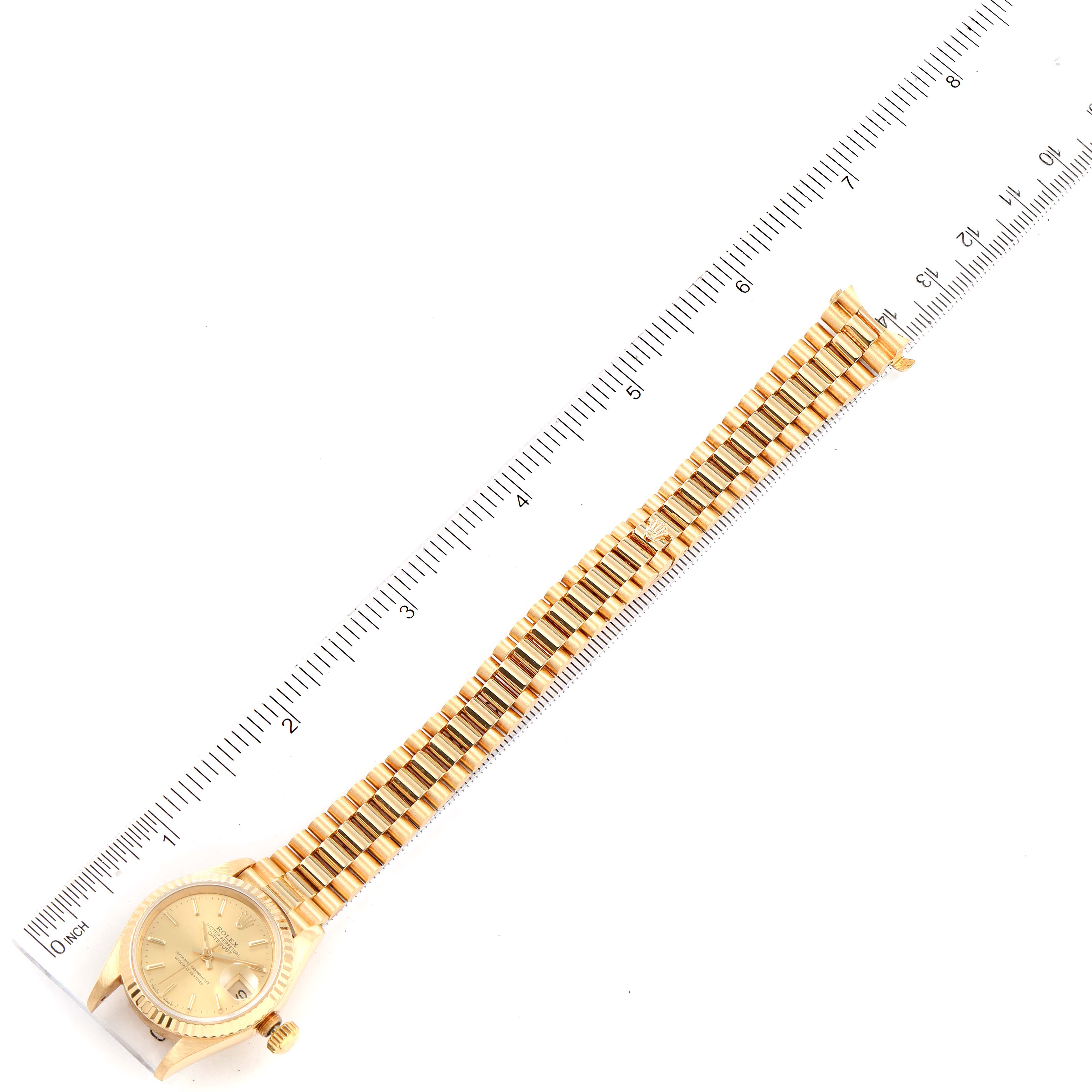 This image shows the full length of the Rolex President 69178 Women
s Yellow Gold Champagne Dial 69178 Women
s Yellow Gold Champagne Dial model watch laying flat next to a ruler for measurement.