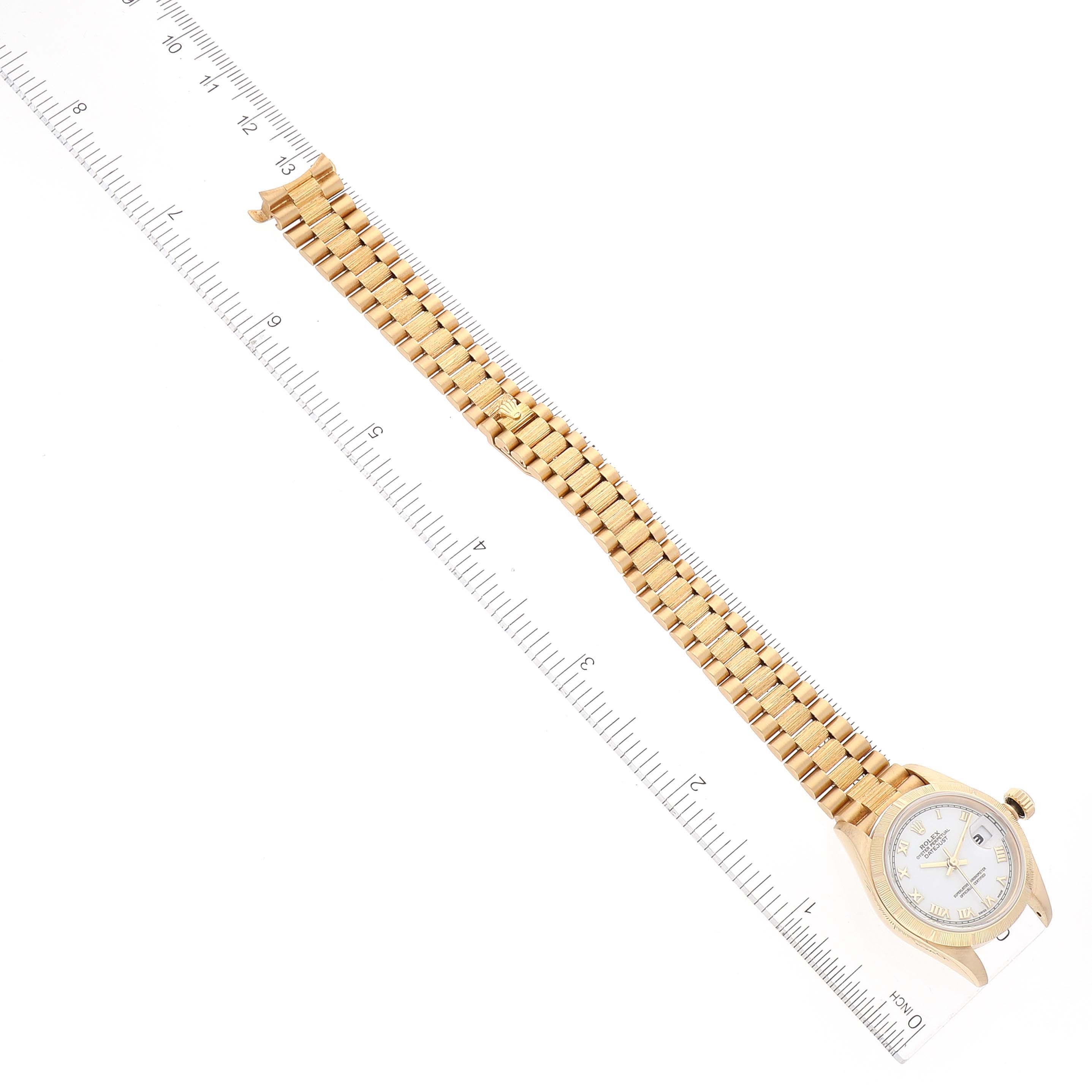 The image shows a Rolex President 69278 Women
s Yellow Gold White Dial 69278 Women
s Yellow Gold White Dial model watch laid flat with a measuring ruler beside it.