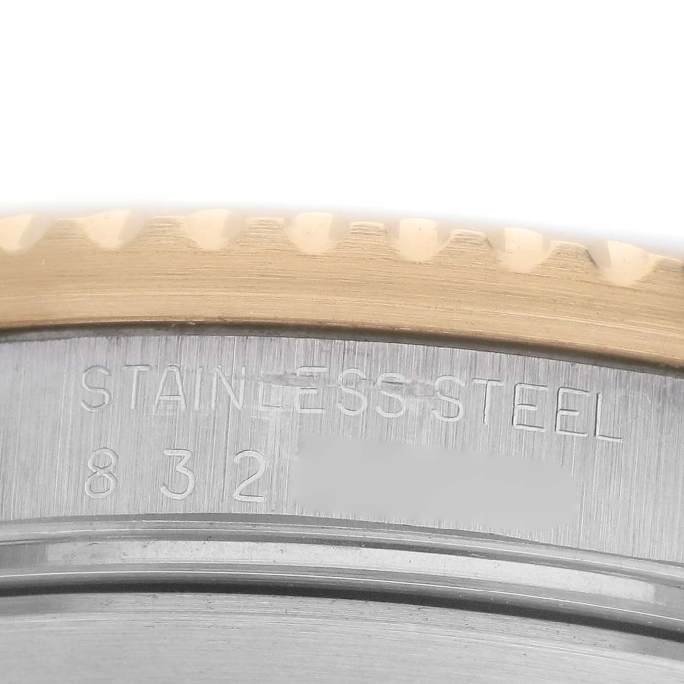 The image shows a close-up of the engraved case back edge of a Rolex Submariner 16803 Men's Steel and Gold (two tone) Black Dial, highlighting the "Stainless Steel" text and numbers.