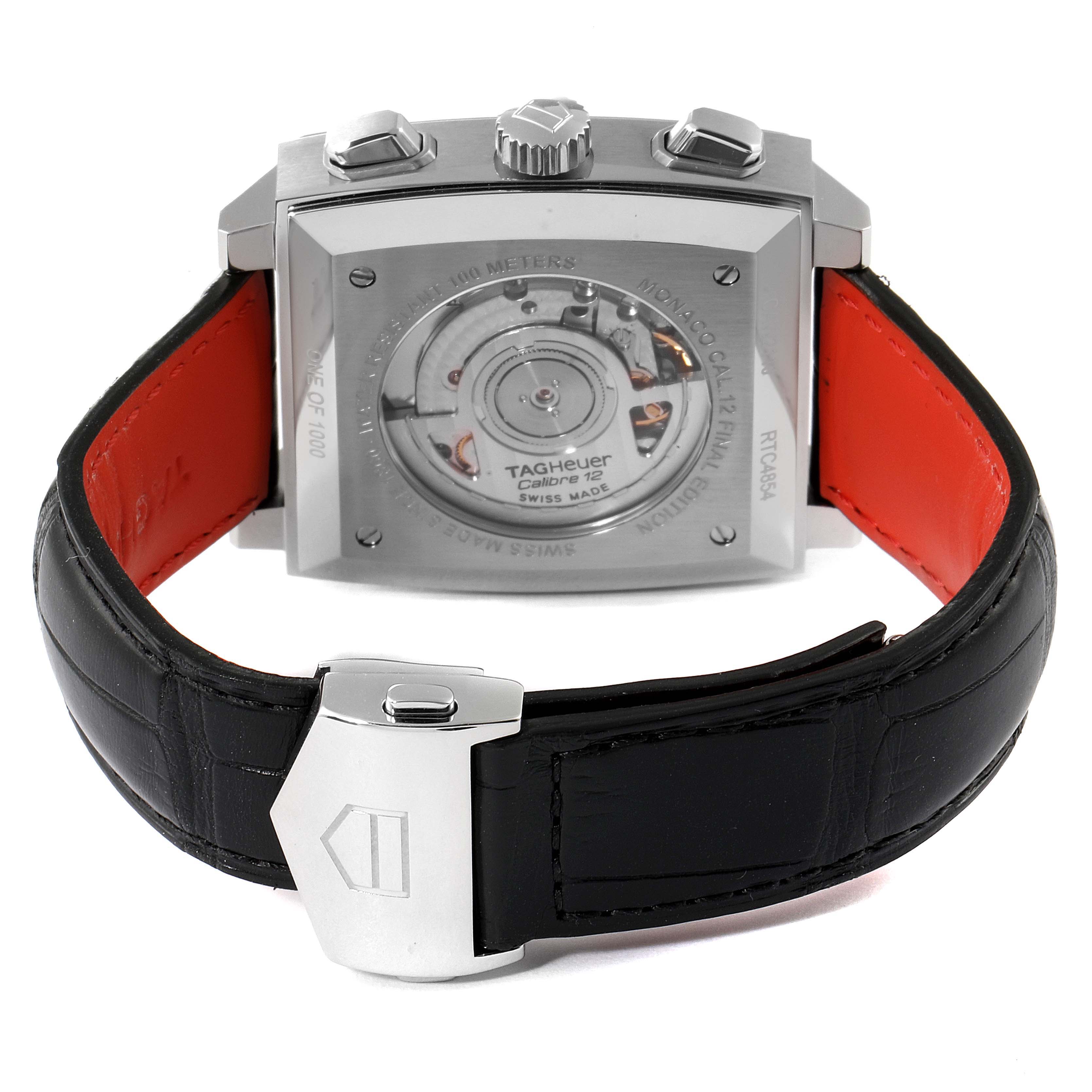 The image shows the back view of the Tag Heuer Monaco watch, highlighting the movement and black leather strap with a clasp.