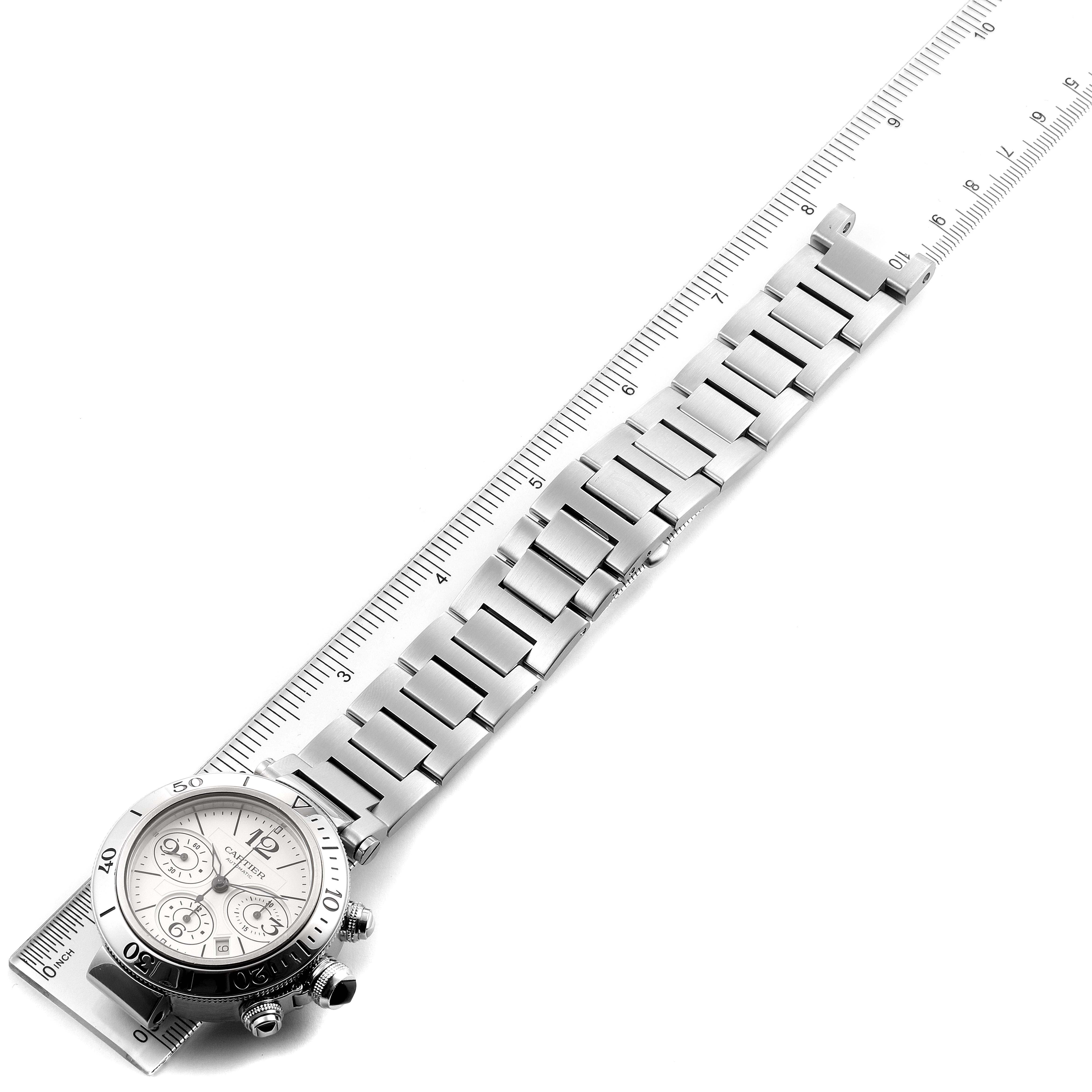 This image shows a top view of a Cartier Pasha W31089M7 Men's Stainless Steel Silver Dial W31089M7 Men's Stainless Steel Silver Dial watch with a metal bracelet laid next to a ruler.