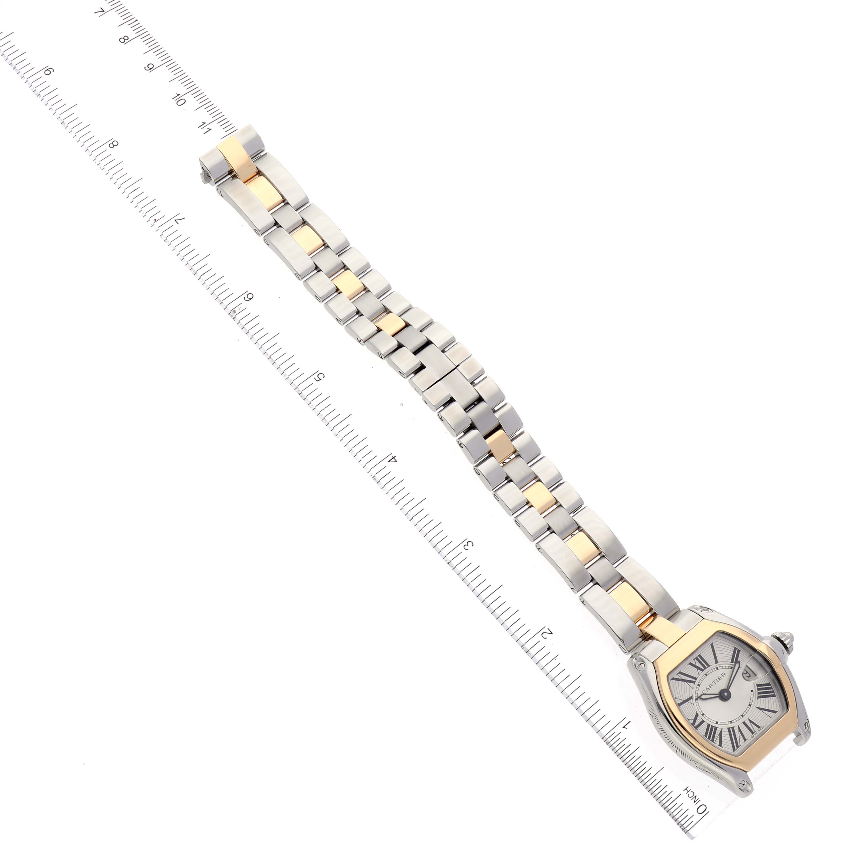 The Cartier Roadster W62026Y4 Women's Steel and Gold (two tone) Silver Dial W62026Y4 Women's Steel and Gold (two tone) Silver Dial watch is shown at a top-down angle, displaying the face and bracelet next to a ruler.