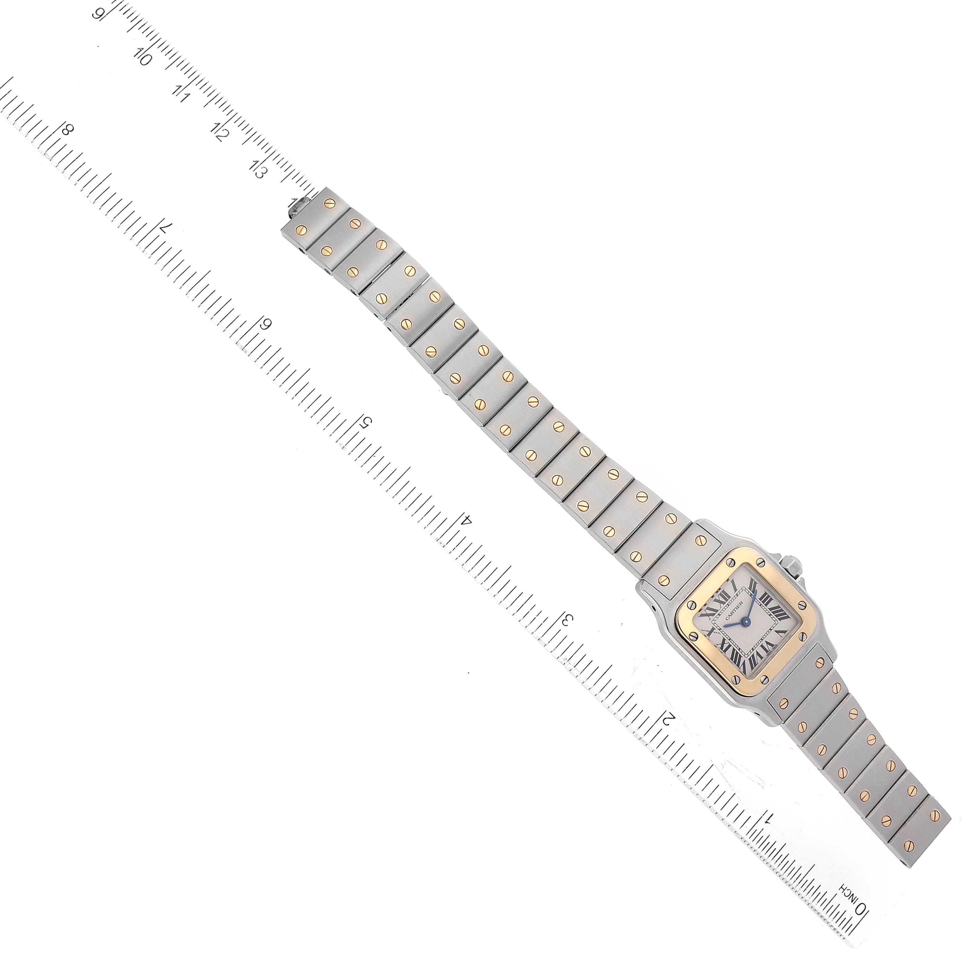 The Cartier Santos W20012C4 Women's Steel and Gold (two tone) Silver Dial W20012C4 Women's Steel and Gold (two tone) Silver Dial watch is shown from a top-down angle, displaying its face, entire bracelet, and a ruler for scale.