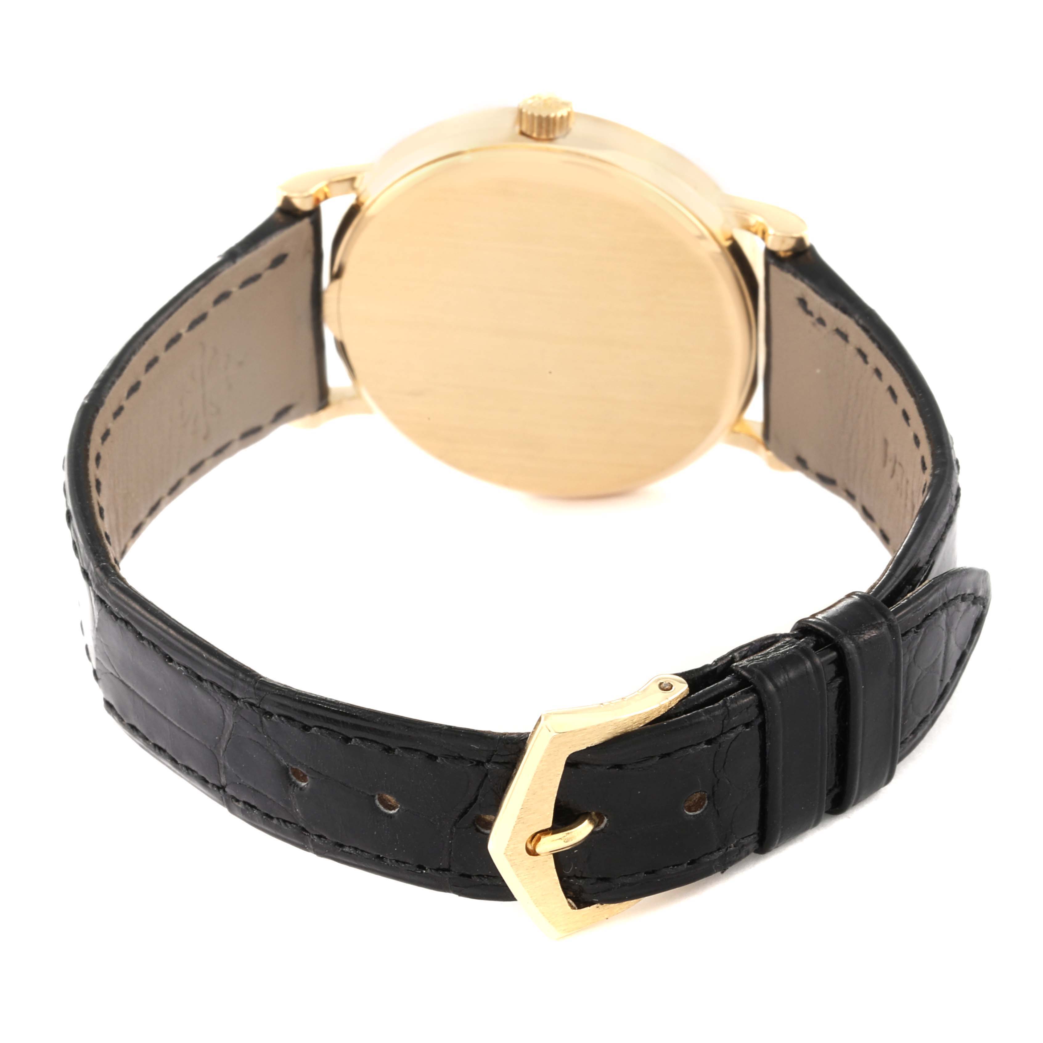 This image shows the back of the Patek Philippe Calatrava 3802/200 Men's Yellow Gold White Dial 3802/200 Men's Yellow Gold White Dial watch, highlighting the gold case, crown, and black leather strap with a gold buckle.