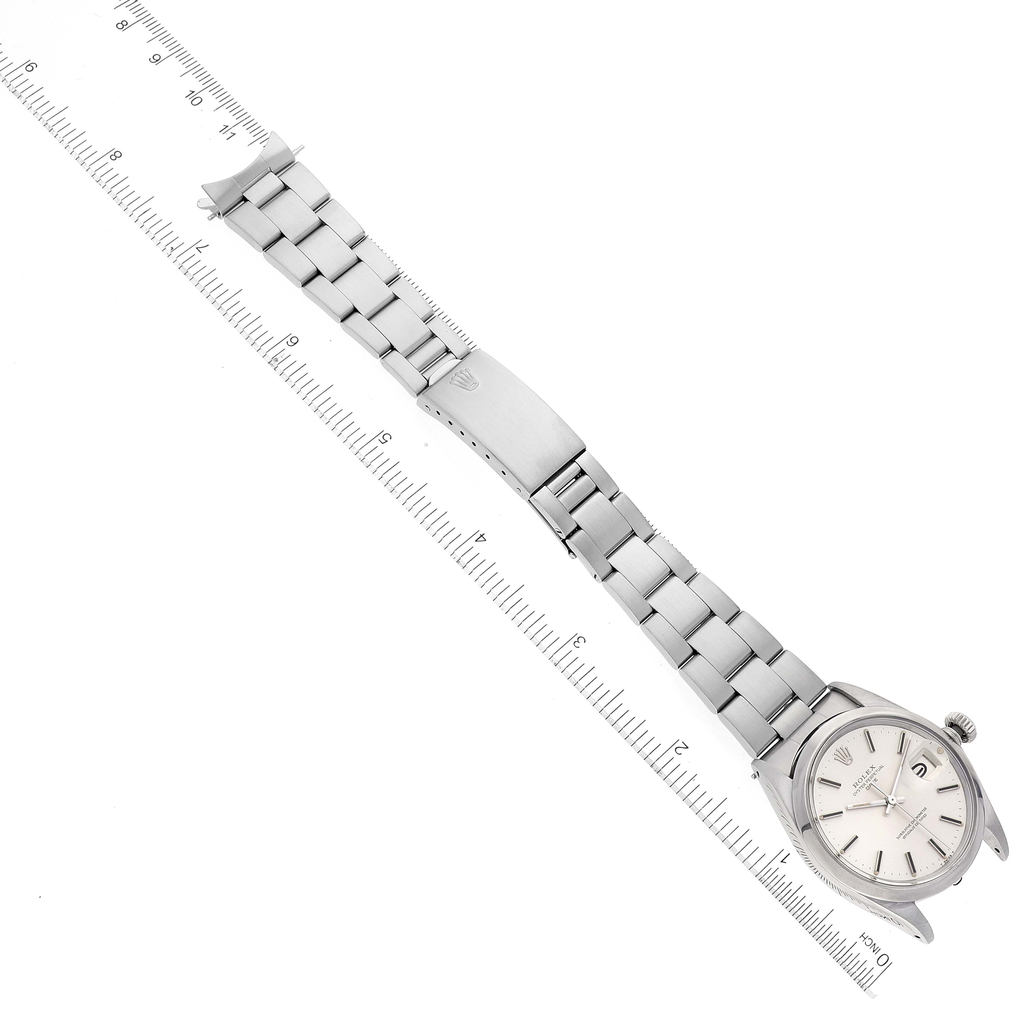 This image shows the Rolex Date 1500 Men
s Stainless Steel Silver Dial 1500 Men
s Stainless Steel Silver Dial model watch laid out flat with a ruler beside it, displaying the bracelet and watch face.