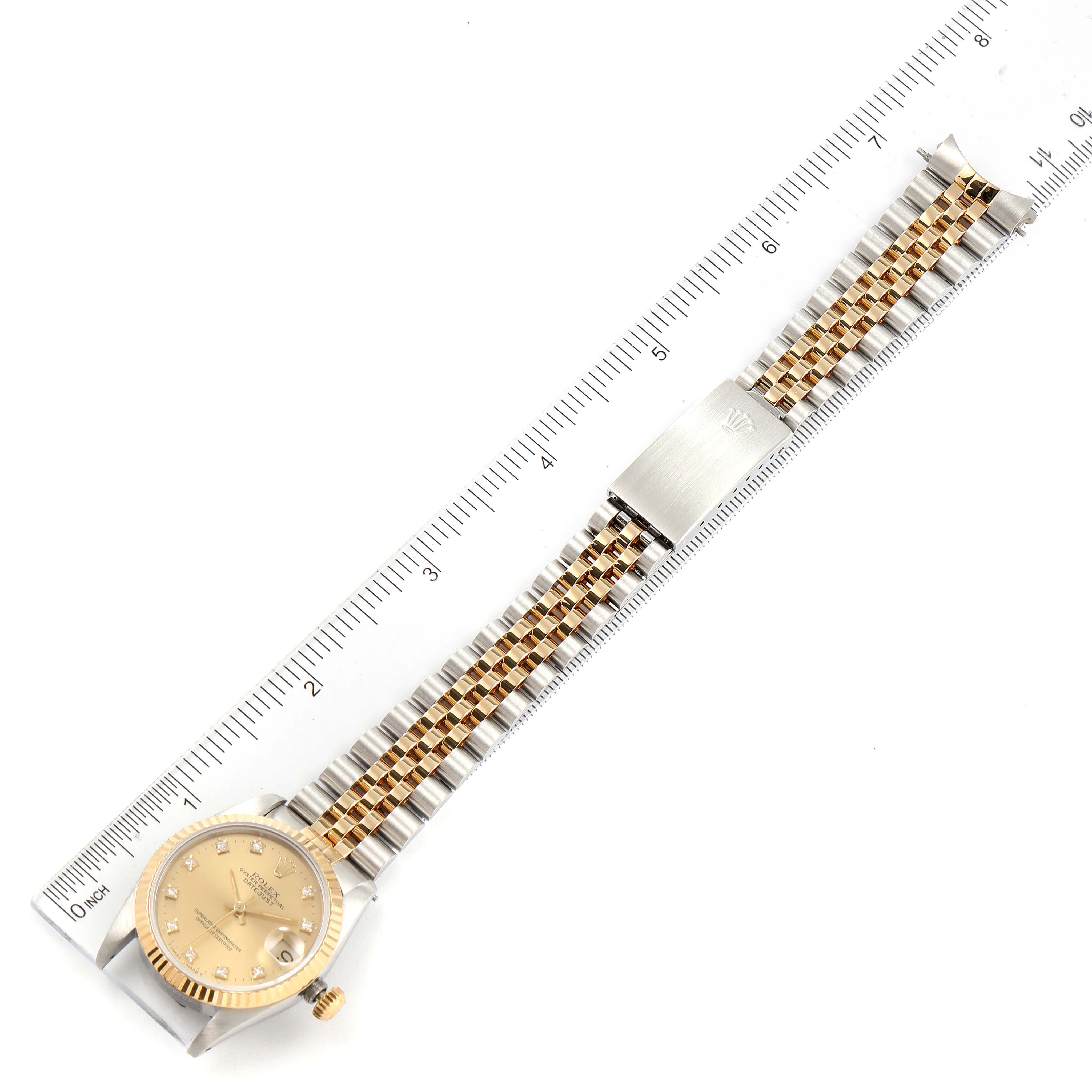 This is a top-down view of a Rolex Mid-Size 68273 Women's Steel and Gold (two tone) Champagne Dial 68273 Women's Steel and Gold (two tone) Champagne Dial watch, showing the face, crown, bezel, bracelet, and clasp against a ruler.