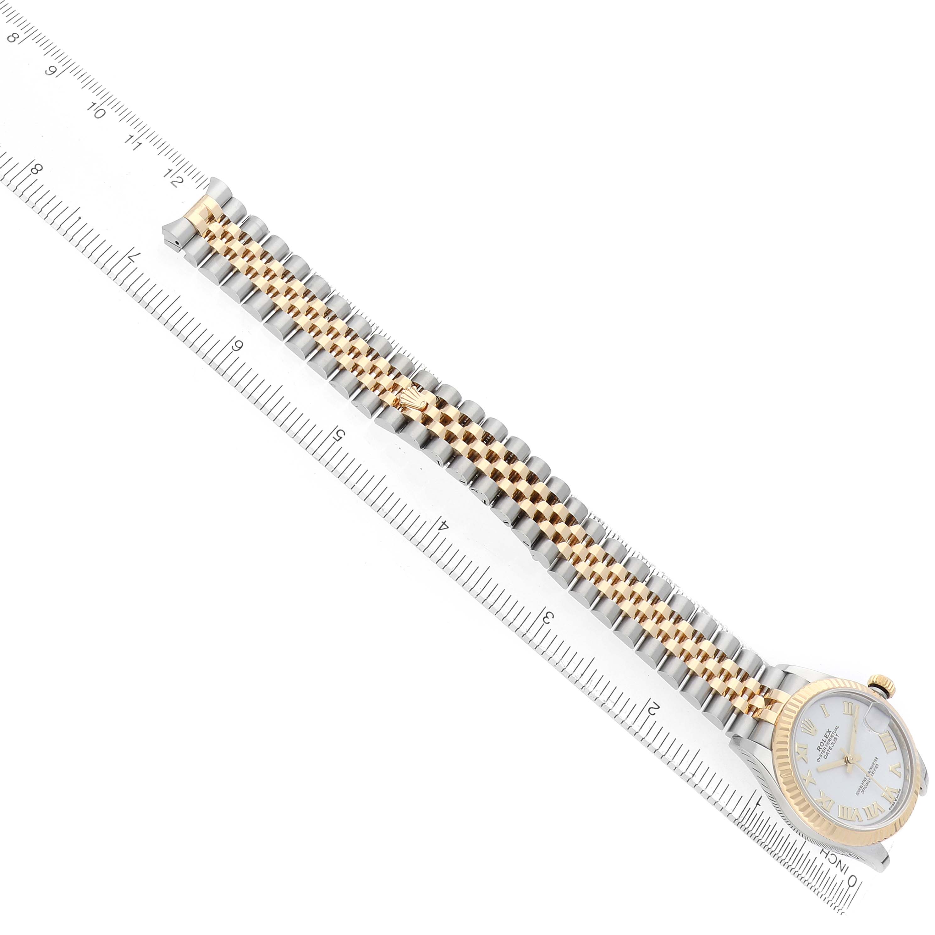 The Rolex Datejust 278273 Women
s Steel and Gold (two tone) White Dial watch is shown from a top-down angle, highlighting the bracelet and the case alongside a ruler.