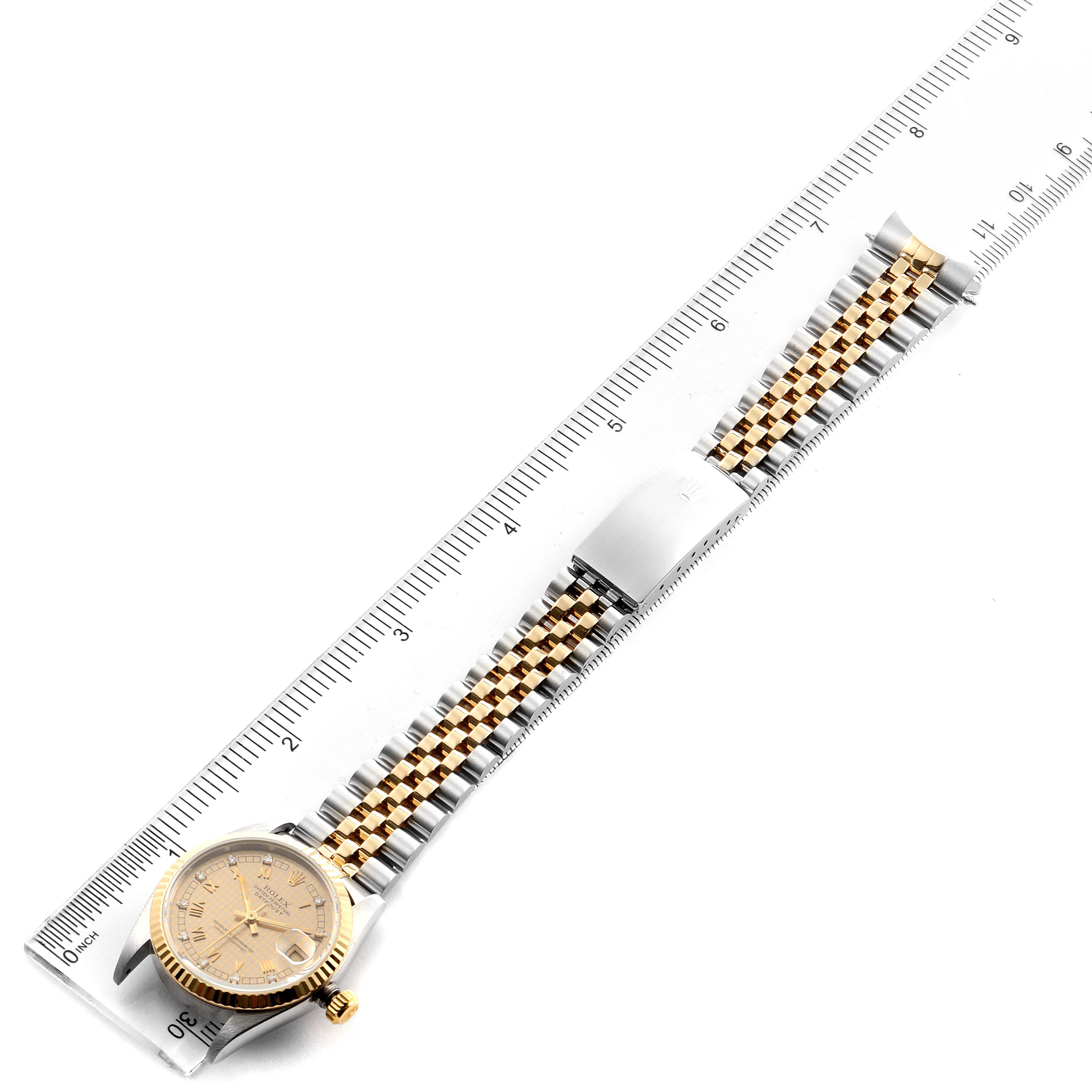 The Rolex Mid-Size 68273 Women's Steel and Gold (two tone) Champagne Dial 68273 Women's Steel and Gold (two tone) Champagne Dial watch is shown from a top-down angle, highlighting the face and two-tone bracelet against a ruler.