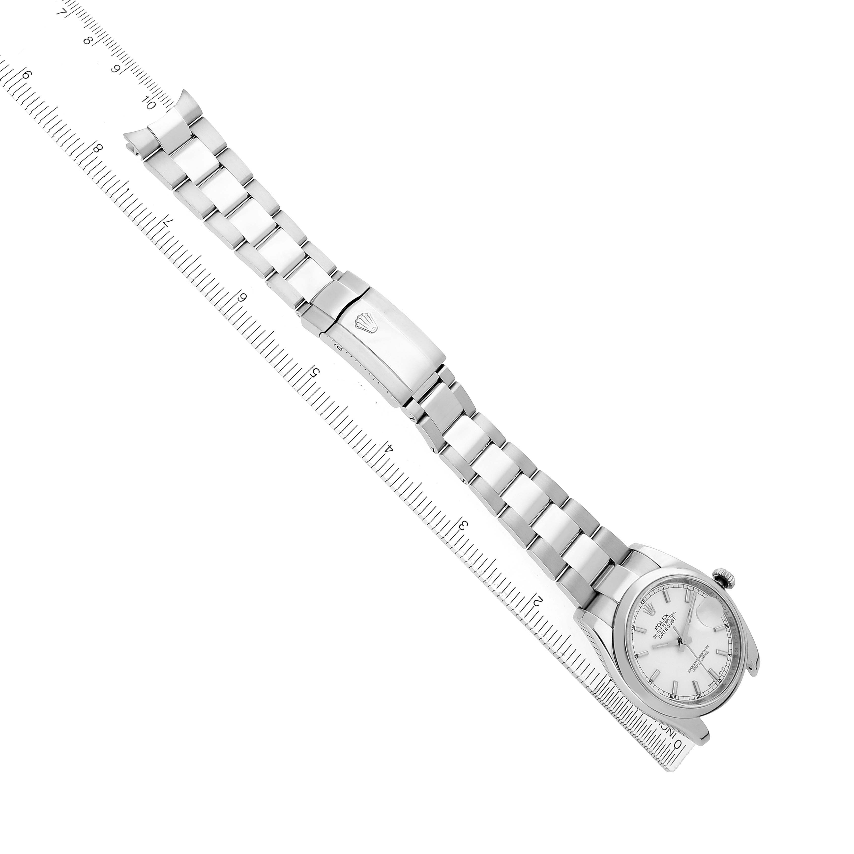 The Rolex Datejust 116200 Men
s Stainless Steel White Dial watch is shown at an angle, highlighting its stainless steel bracelet and clasp, alongside a ruler.
