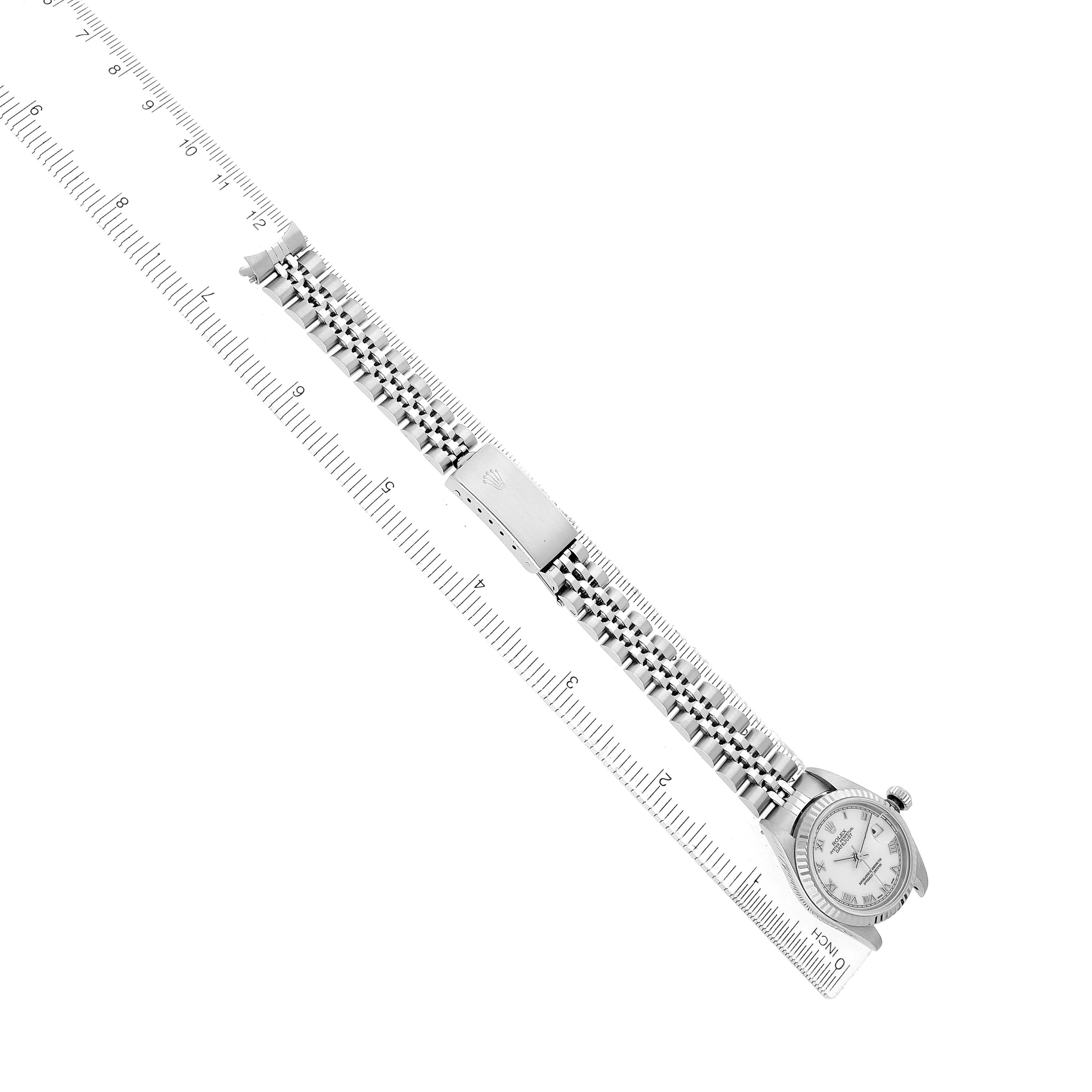 The Rolex Datejust 79174 Women's Stainless Steel White Dial watch is shown from an overhead angle, displaying the bracelet and clasp alongside a measuring ruler.