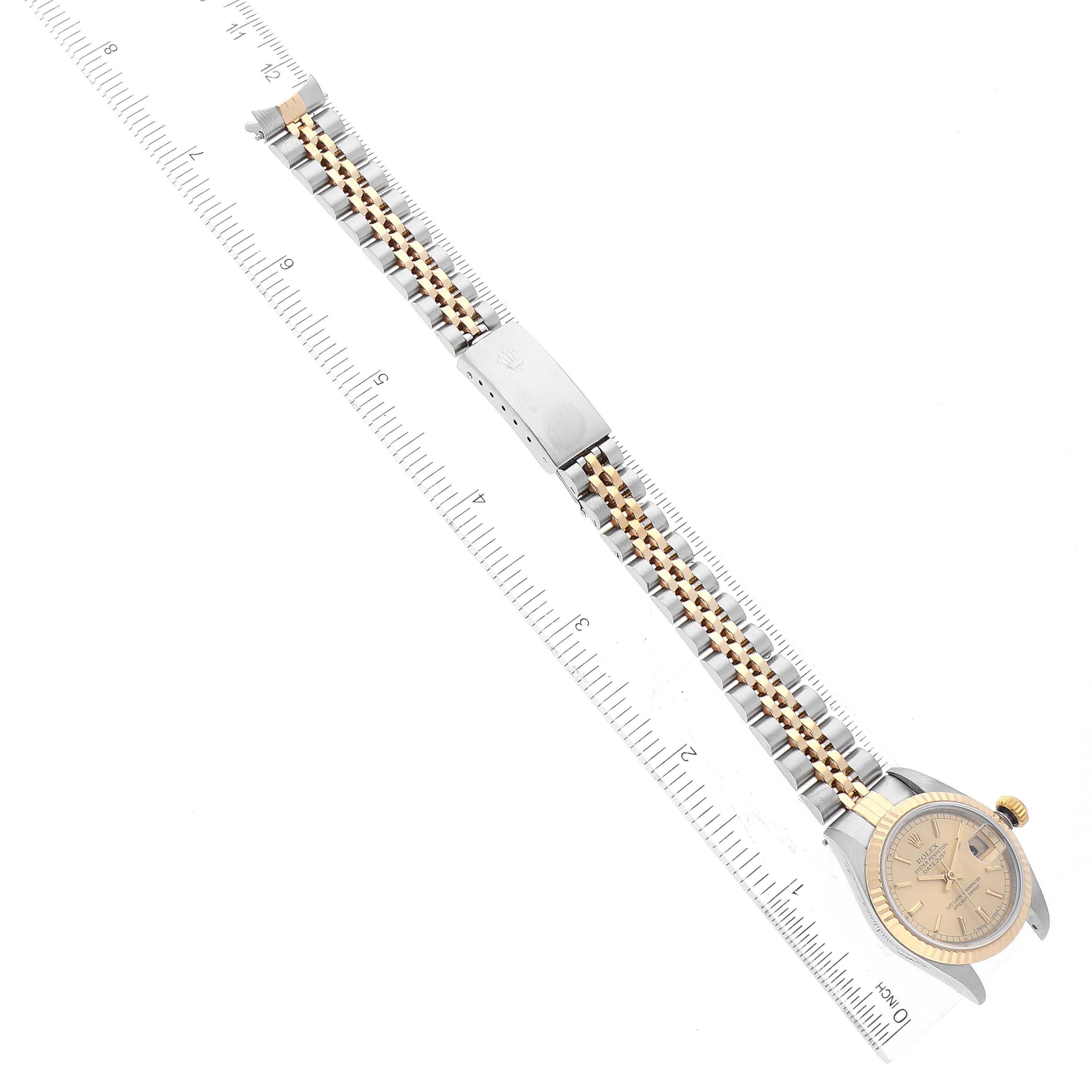 This image shows a Rolex Datejust 79173 Women's Steel and Gold (two tone) Champagne Dial 79173 Women's Steel and Gold (two tone) Champagne Dial watch laid flat, showcasing the watch face and its two-tone bracelet alongside a ruler.
