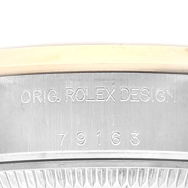 This image shows a close-up of the side of a Rolex Datejust 79163 Women's Steel and Gold (two tone) Mother of Pearl Dial 79163 Women's Steel and Gold (two tone) Mother of Pearl Dial watch with the engraving "ORIG. ROLEX DESIGN 79163."